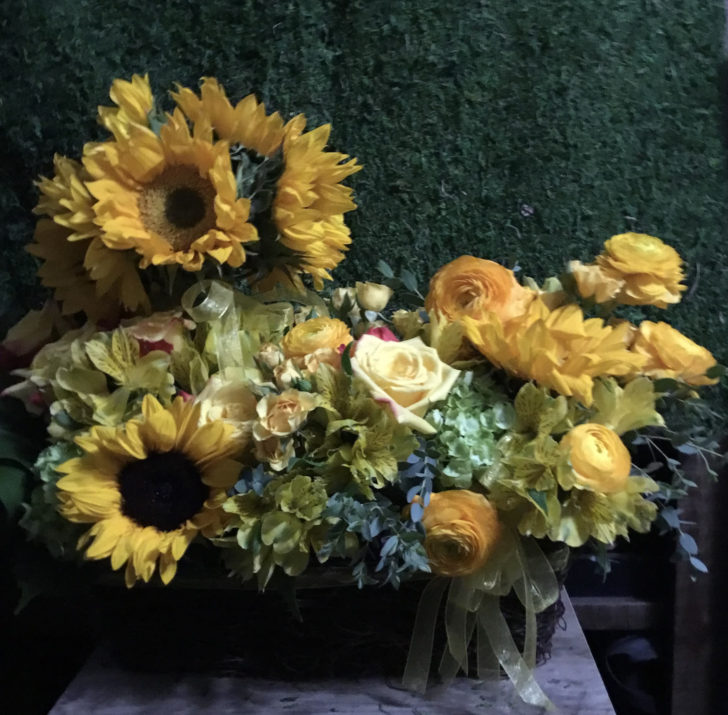 Yellow sunflowers and mixed blooms in a low basket arrangement