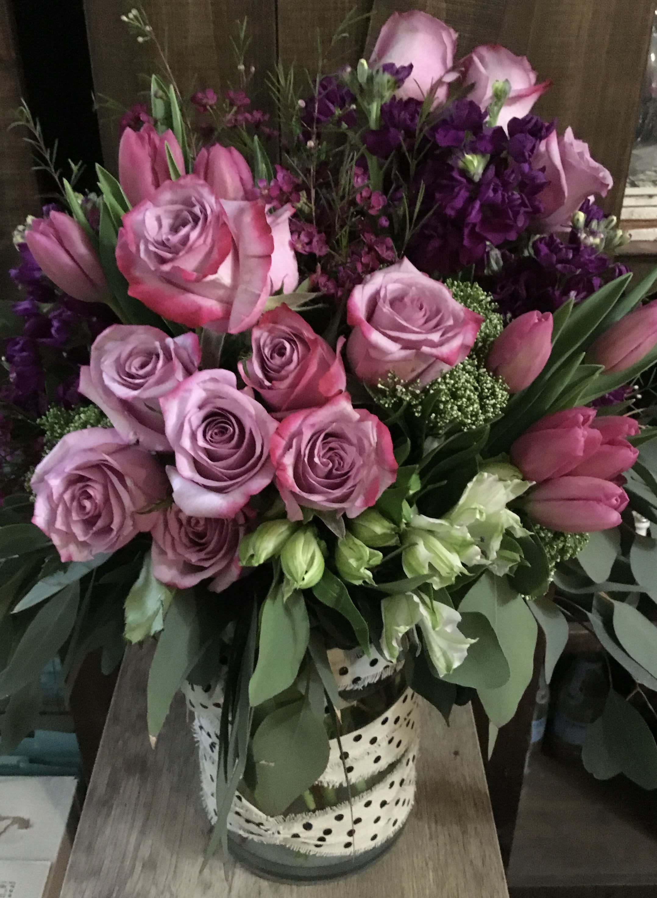 Pink and lavender roses with tulips in a spotted vase