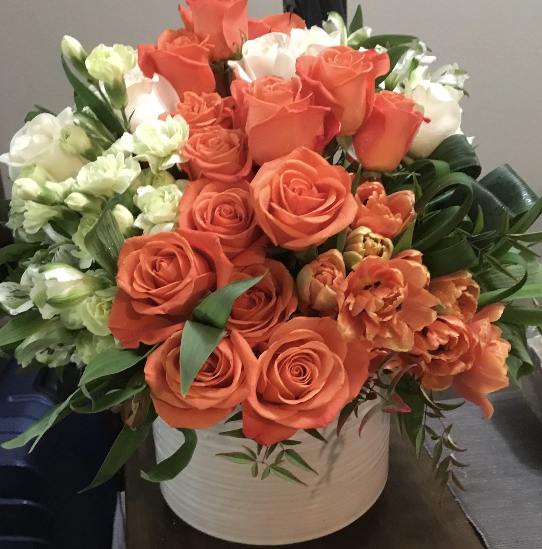 Orange and white roses with orange tulips in a white vase