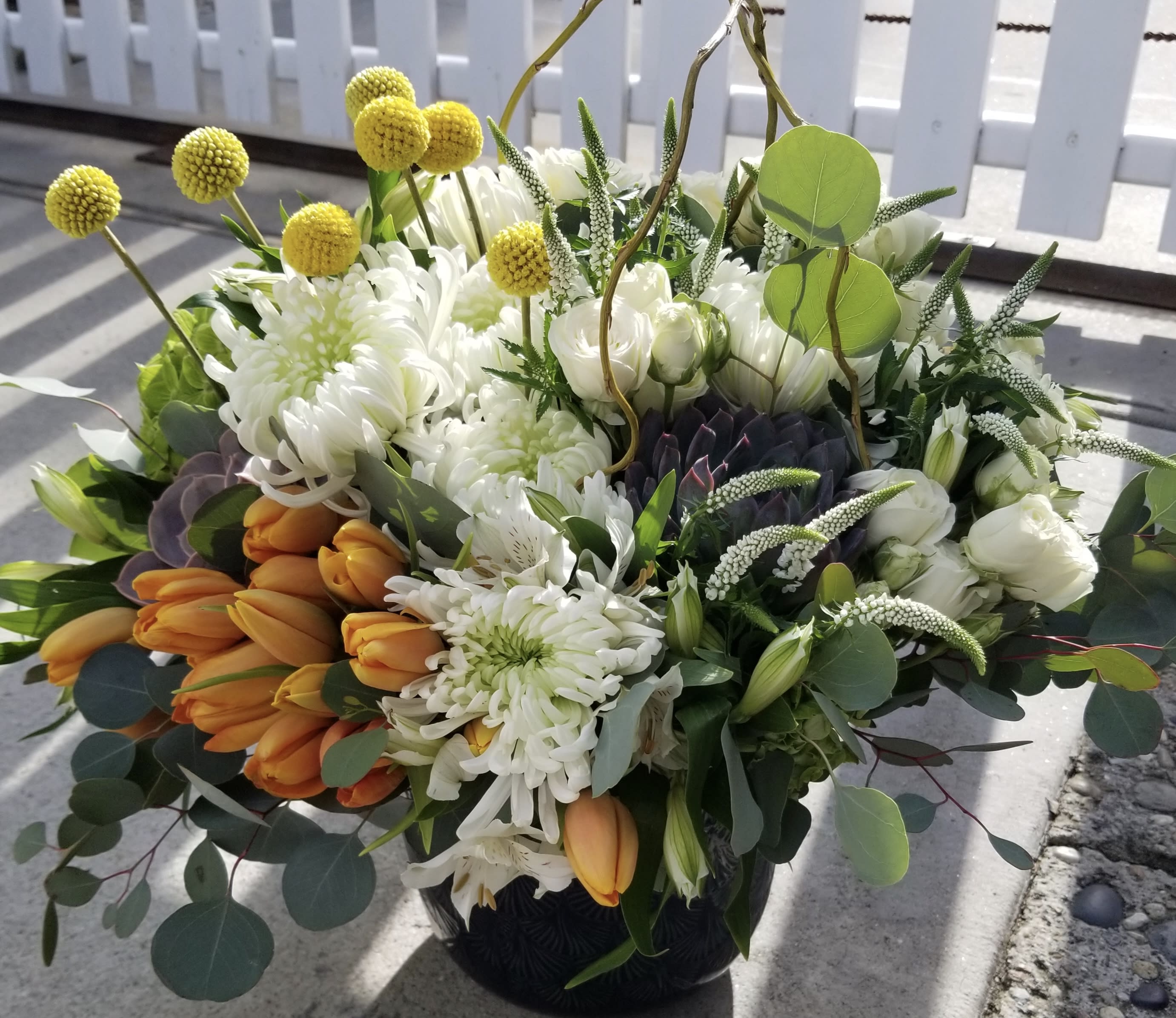 Bouquet of white chrysanthemums and orange tulips in a dark vase