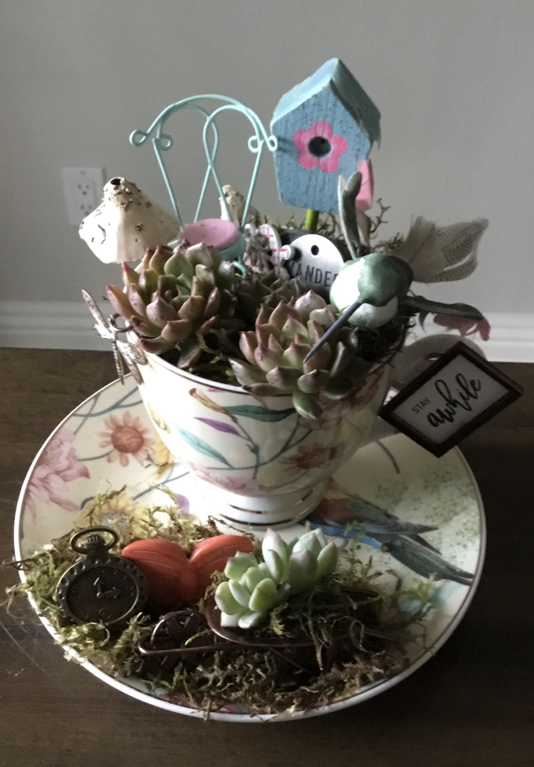 Succulent arrangement in a floral teacup with birdhouse and decorative accents