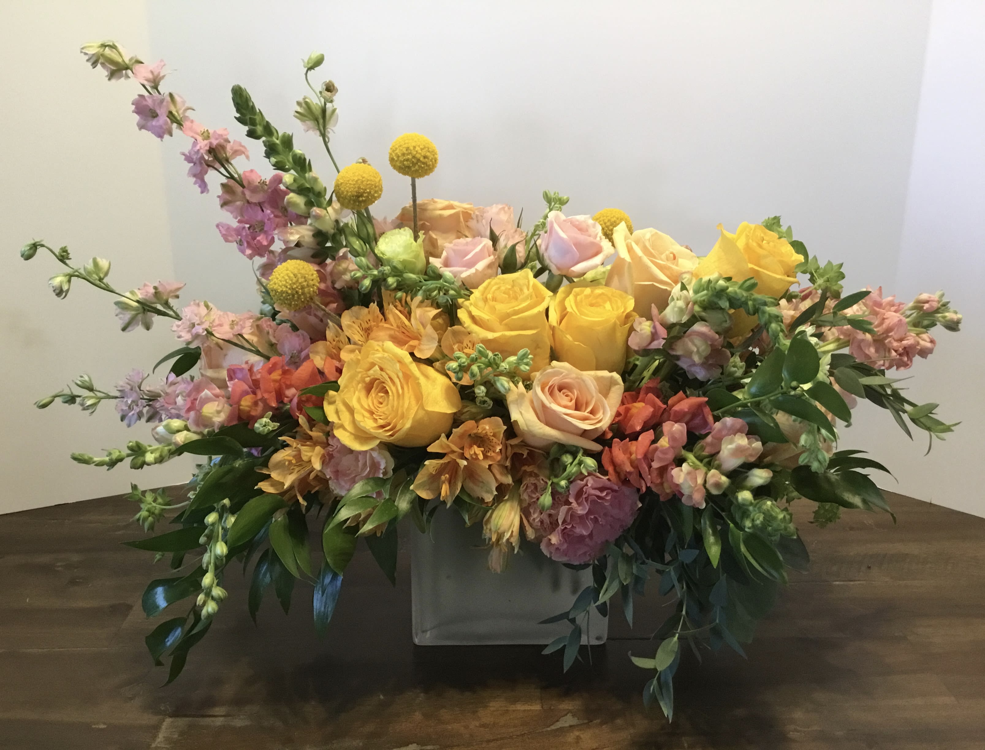 Mixed bouquet of yellow and pink roses in a low white container