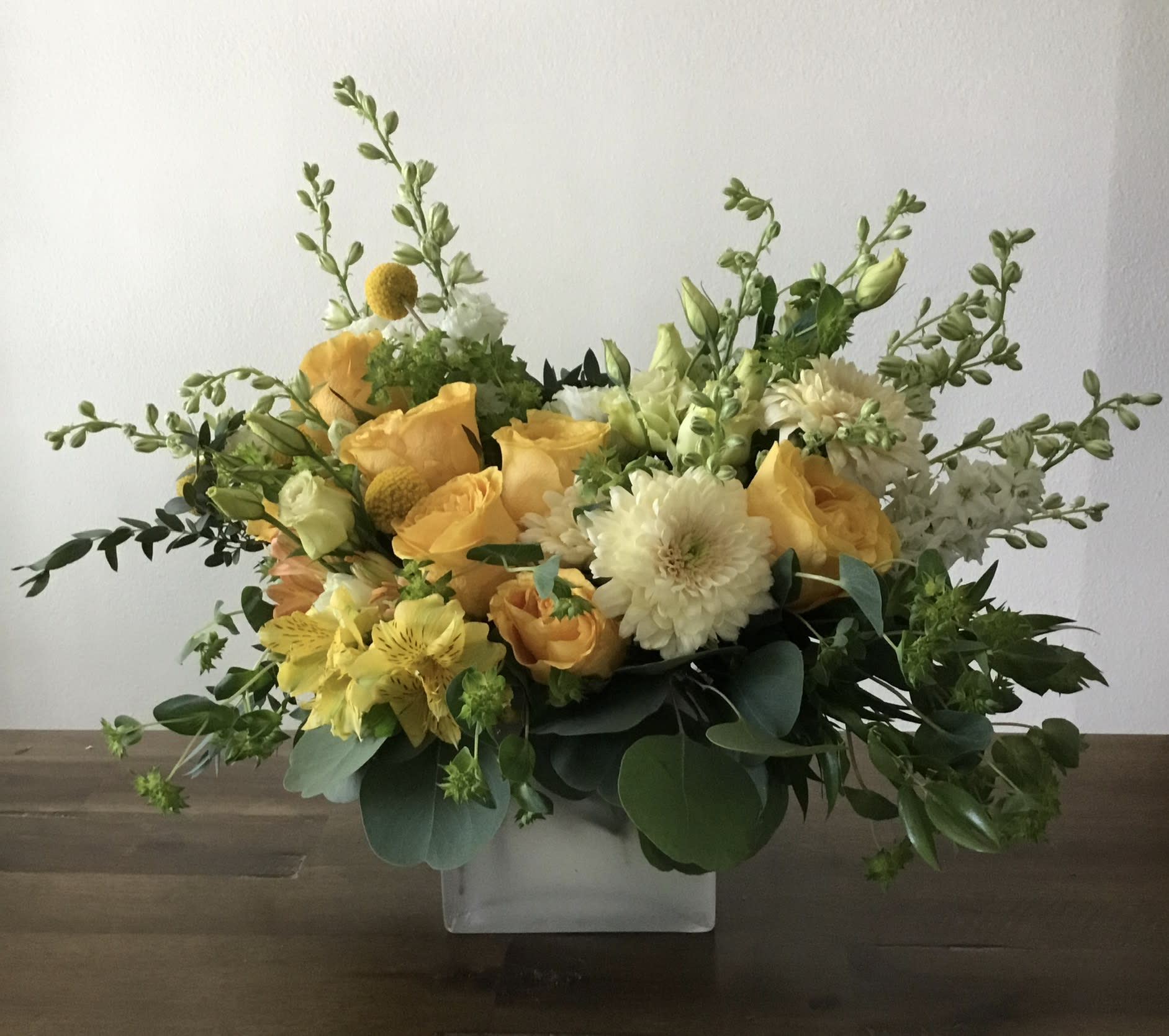 Yellow and white floral arrangement in a clear square vase