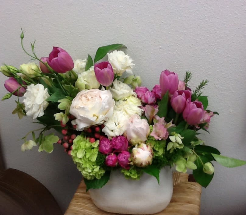 Pink tulips and white flowers arranged in a white vase