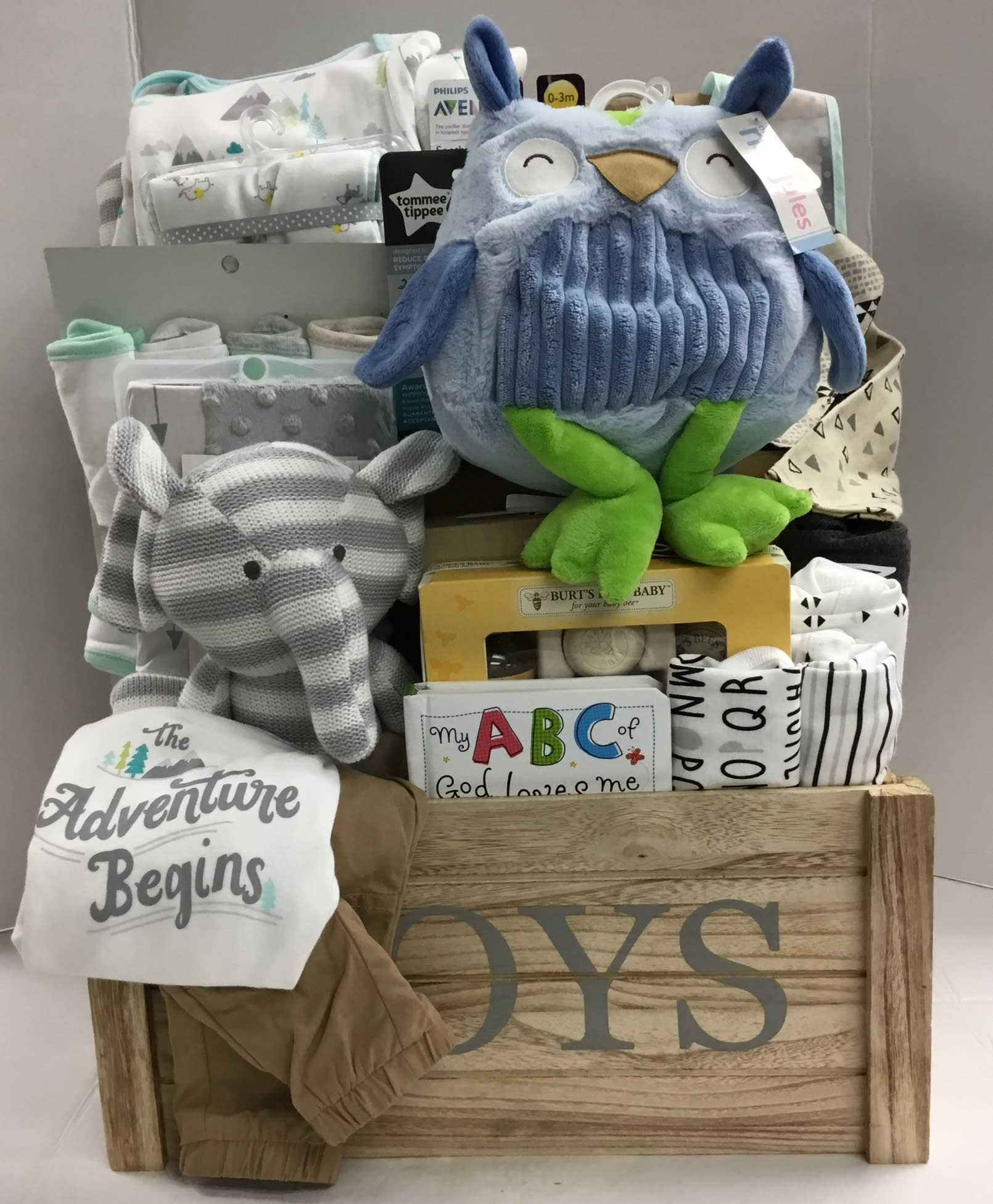 Baby gift basket with blankets, plush toys, and clothing in a wooden crate