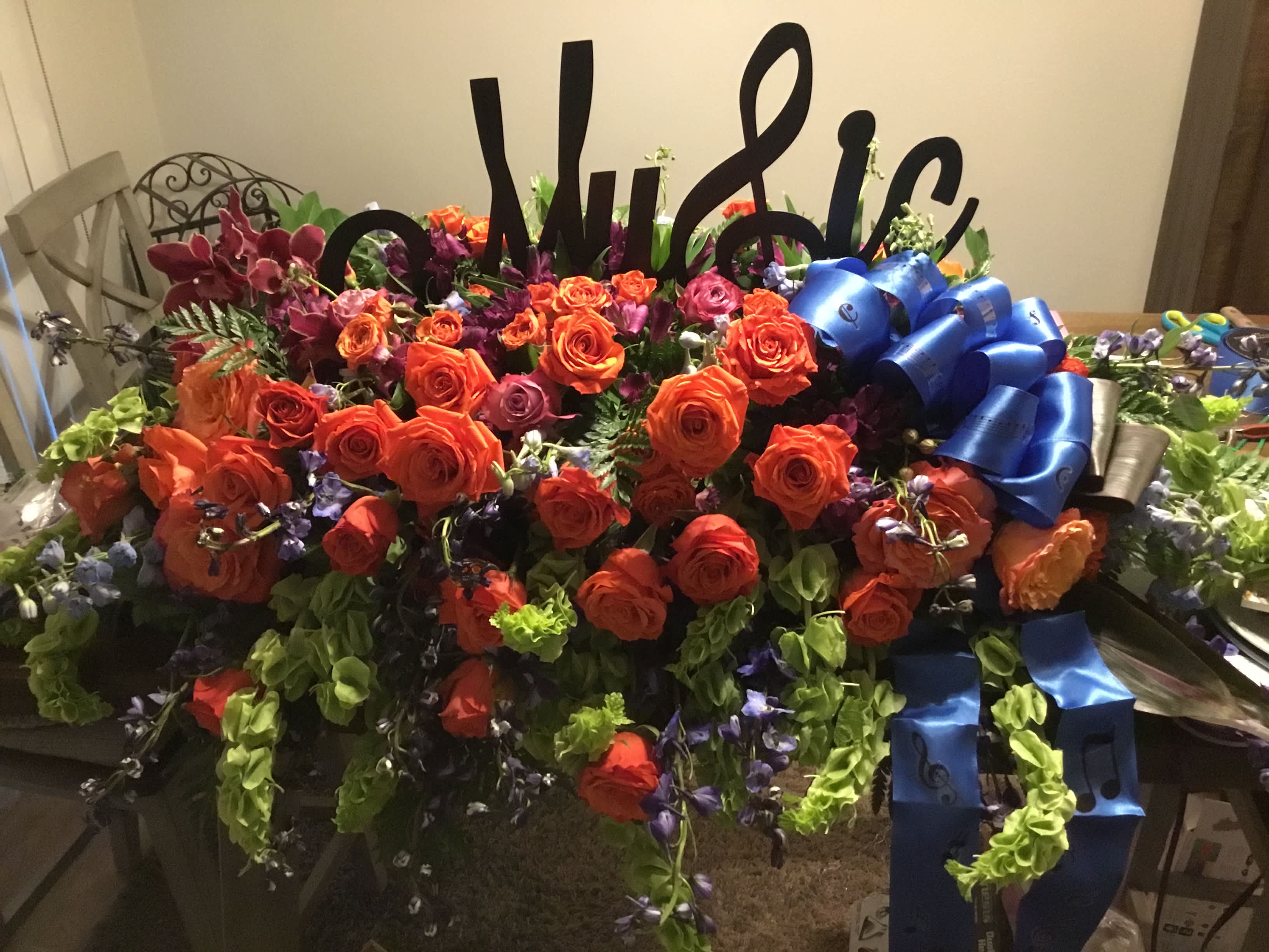 Large floral arrangement with orange roses and blue ribbons
