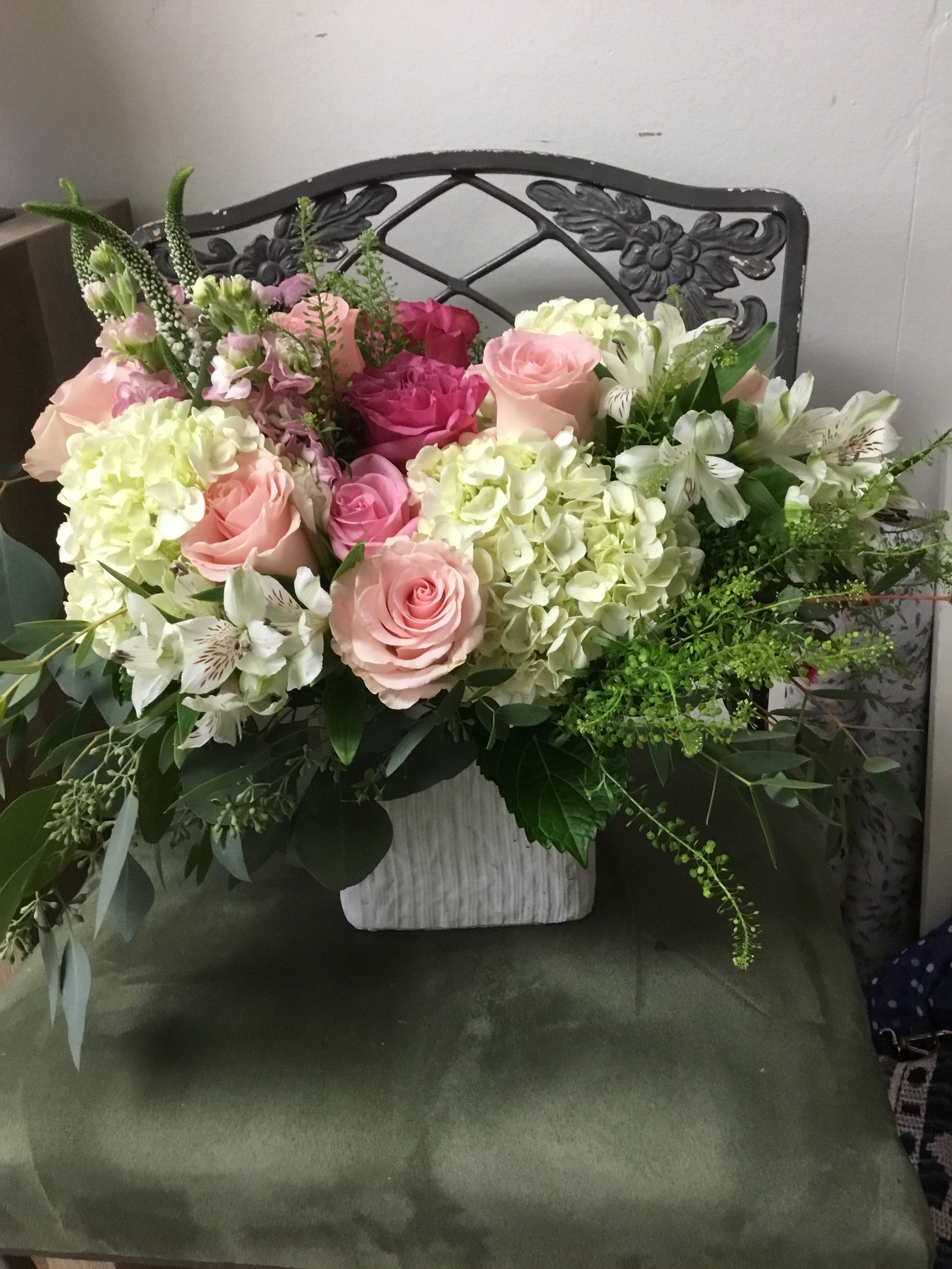 Garden Grace - Soft blush roses nestled in creamy white hydrangeas make Garden Grace an effortlessly romantic flower arrangement for Mother's Day, anniversaries, weddings, or a "thinking of you" surprise. This low-and-wide bouquet blends pink and white blooms with abundant green foliage to create a lush, garden-style look that reads fresh and generously composed-perfect for love and romance or a gentle sympathy and funeral tribute.  The composition pairs clustered pink roses and spray roses with creamy white hydrangeas, white alstroemeria, and fragrant stock for layered texture and subtle scent. Set in a clean white vase, the design feels elegant but relaxed, with airy stems and plenty of greenery giving a hand-arranged, natural silhouette. Dimensions and container are larger than our standard design to deliver more blooms and a fuller presence on tabletops or reception tables.  Whether sent as a birthday surprise, a spring centerpiece, a get-well lift, or a thoughtful gesture during Breast Cancer Awareness Month, Garden Grace is the kind of bouquet that makes the recipient feel truly seen and cared for. Care is simple: keep water fresh and trim stems every few days to maintain vibrancy; if you need delivery timed for a special service or celebration, choose the delivery date at checkout.