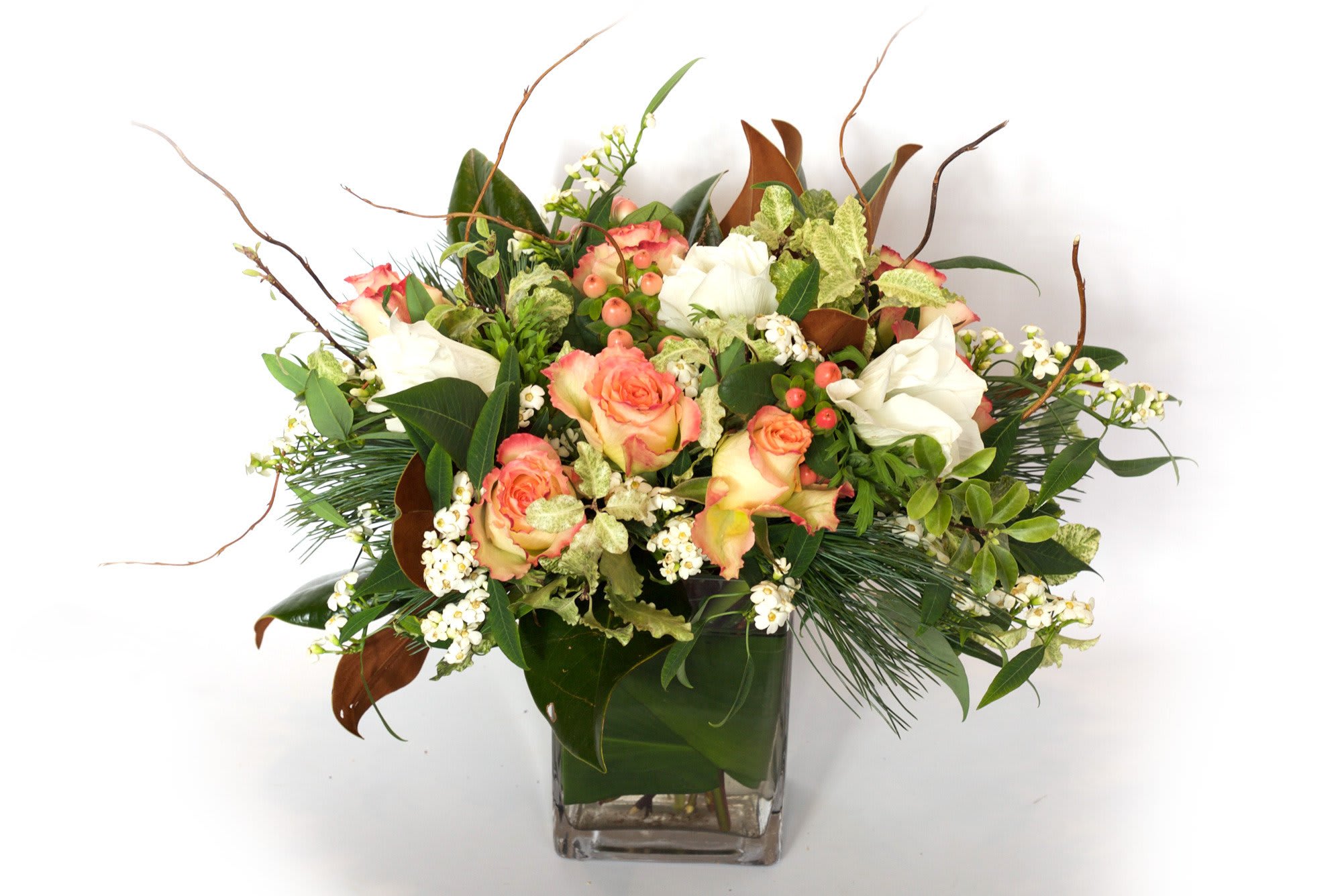 Peach and white roses in a square glass vase with mixed greenery