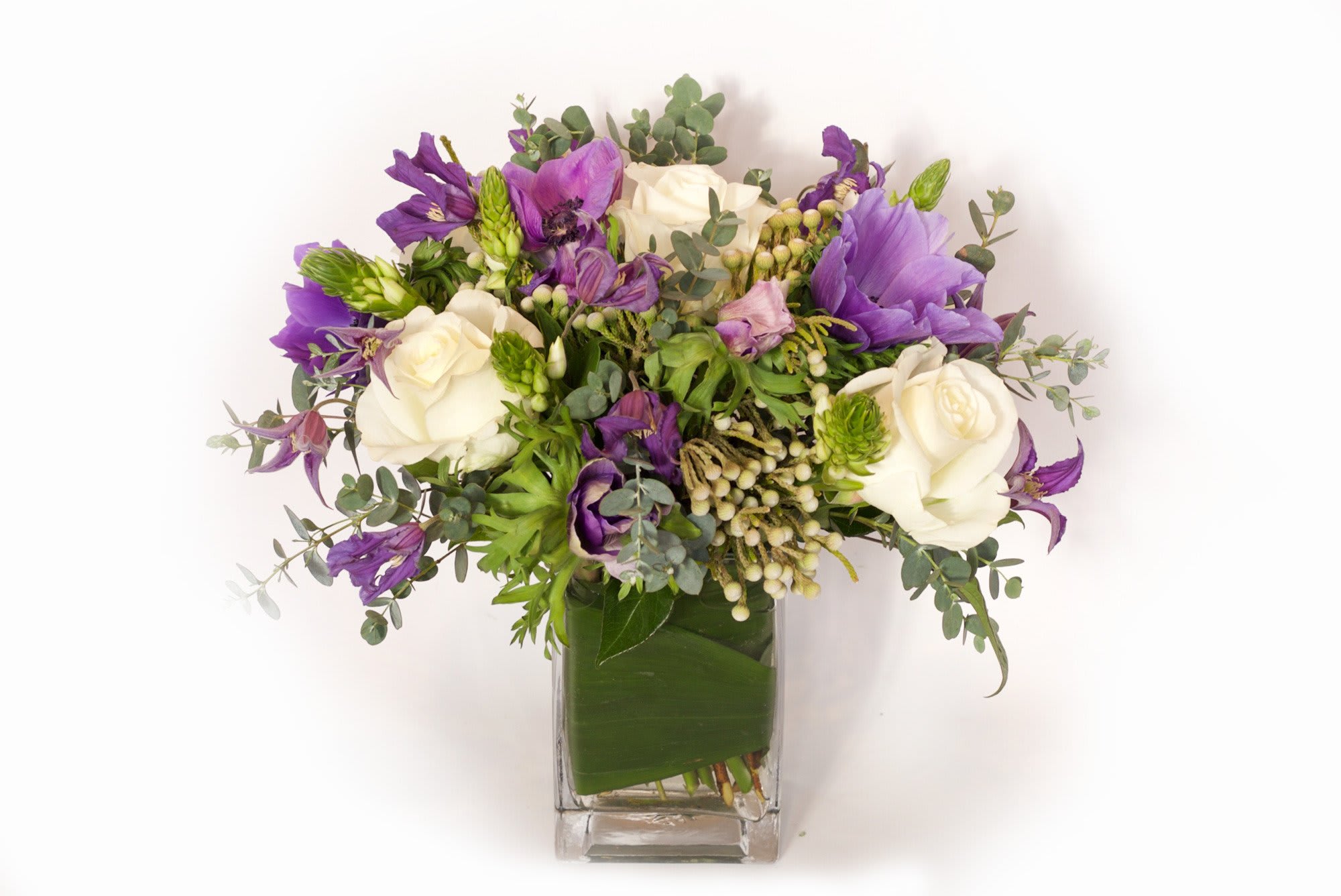Purple and white flower bouquet in a clear square vase