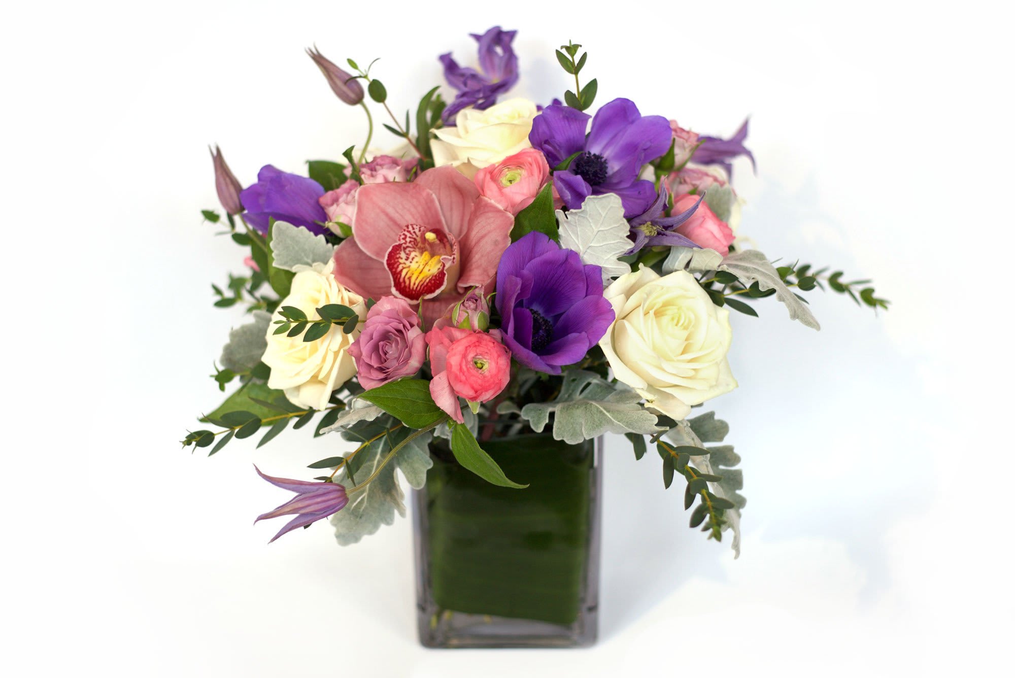 Bouquet of purple, pink, and white flowers in a square glass vase