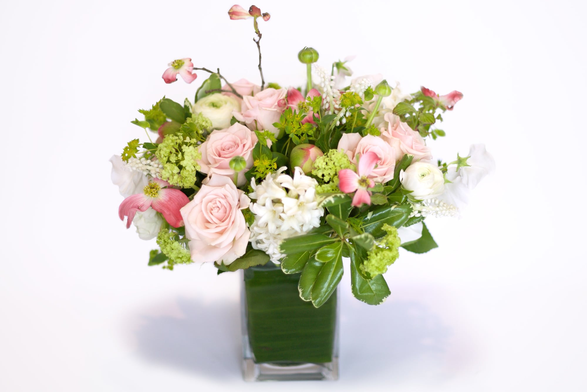 Pink roses and white blooms arranged in a square glass vase