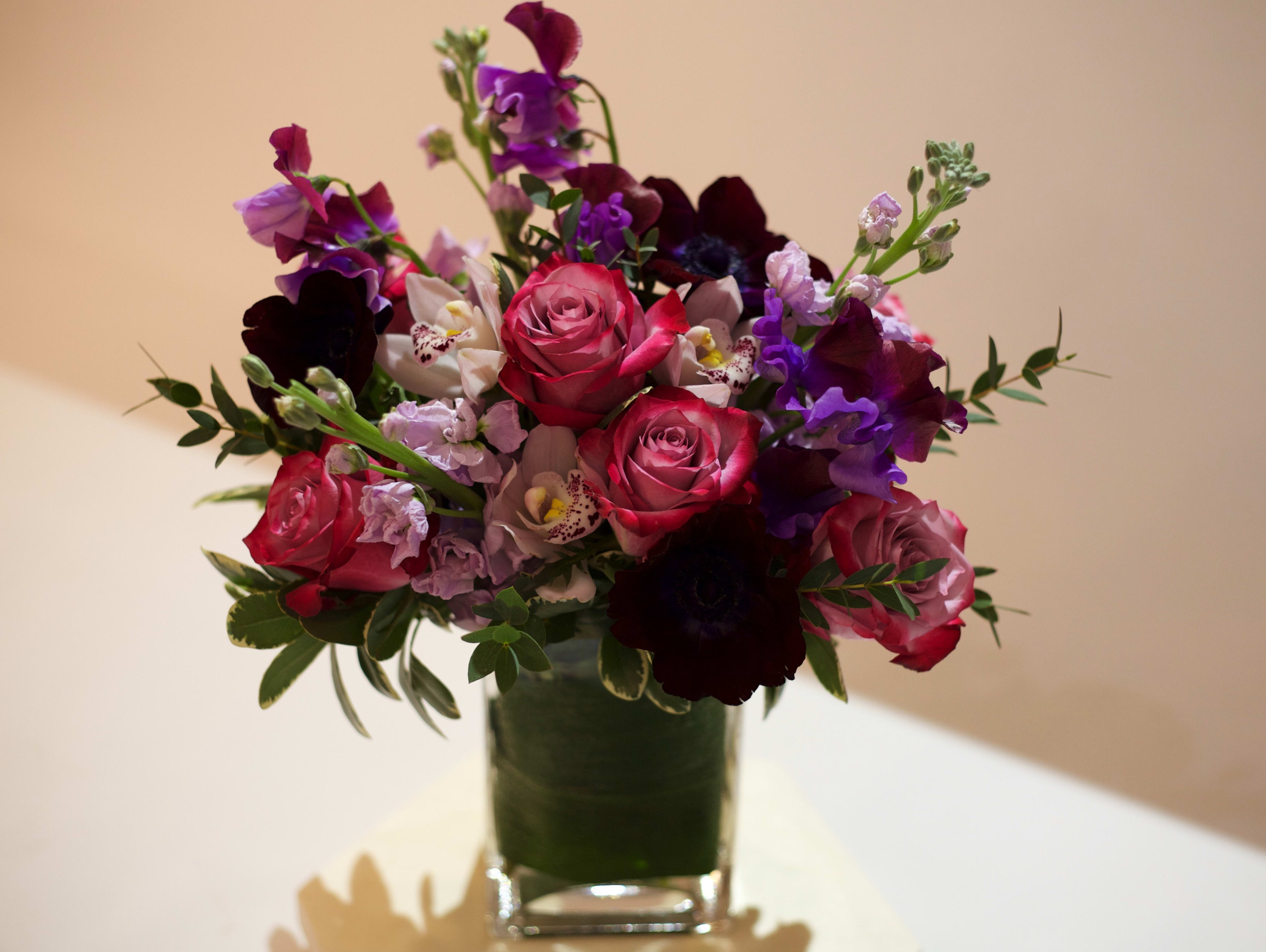 Mixed bouquet of pink, purple, and white flowers in a clear glass vase