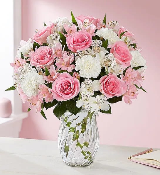 Pink roses and white flowers arranged in a clear glass vase