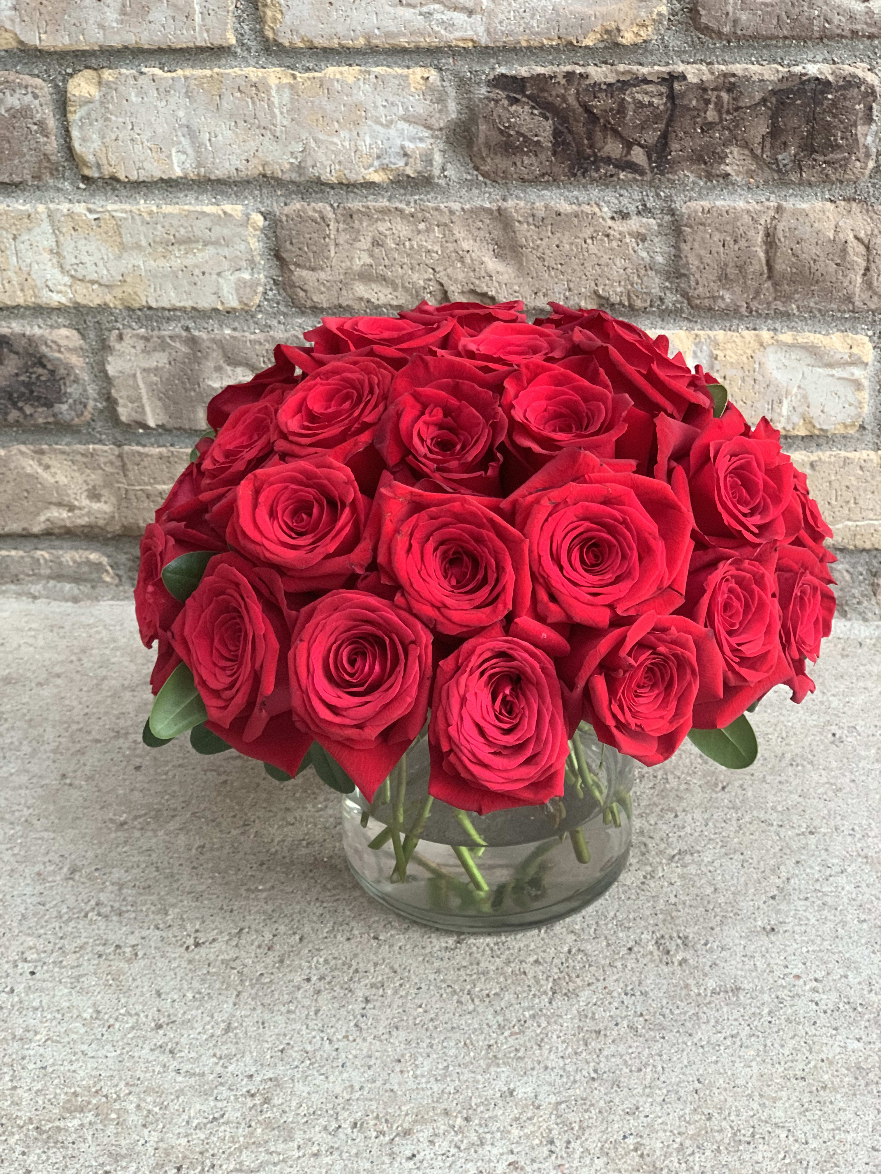 Three Dozen Red Roses  - A beautifully simple design of three dozen premium red roses perfectly arranged in a clear glass vase. This medium sized compact arrangement makes a bold statement whether in a office or home. 
