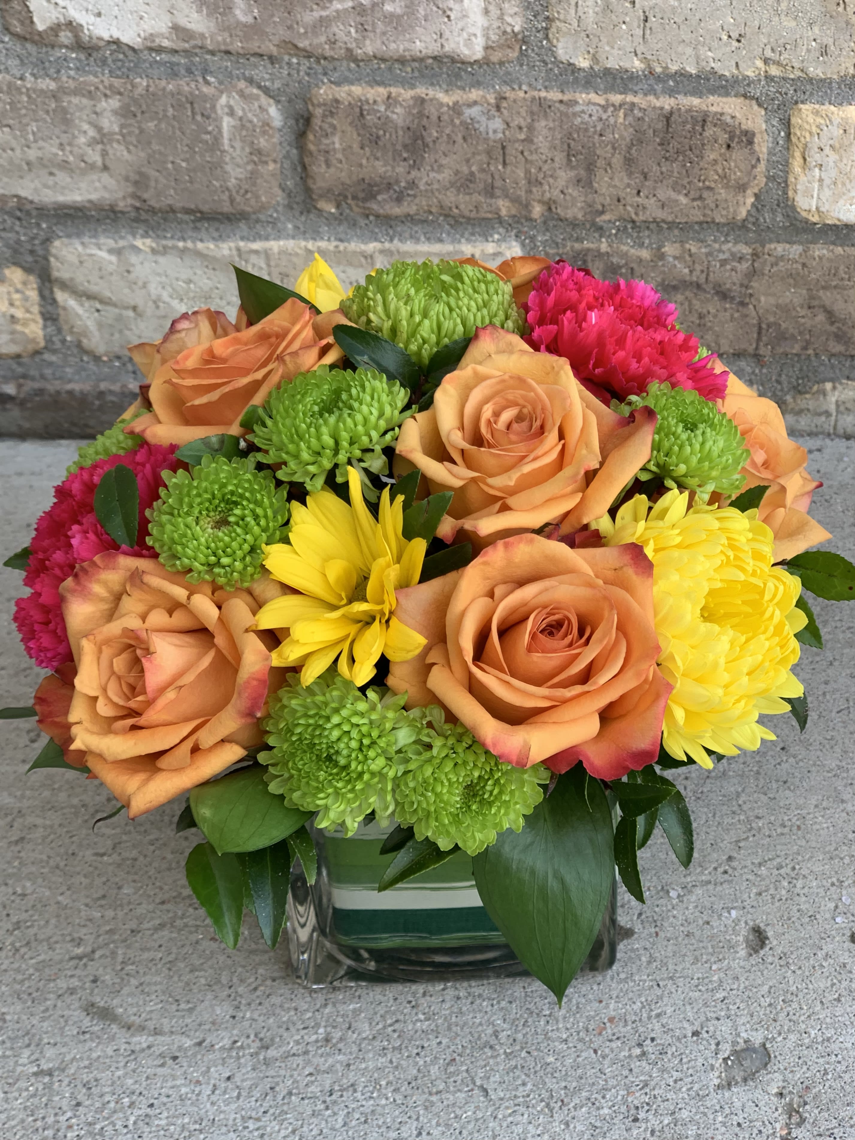 Tropical Kiss - A modern arrangement featuring roses, daisies and carnations in hues of orange, pink, yellow and green.   Colors may vary slightly due to availability. 