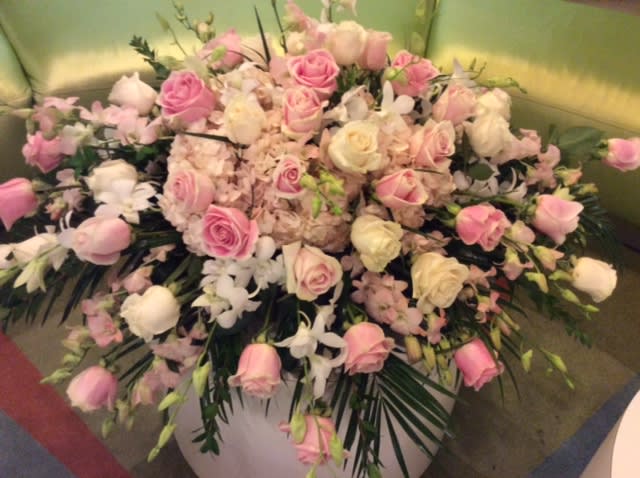 Large pink and white rose arrangement in a white container