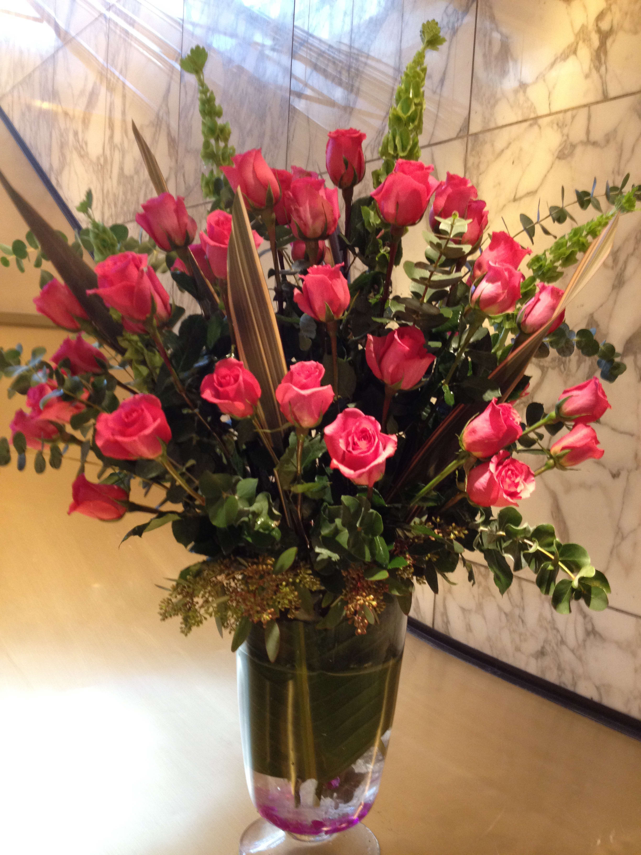 Tall bouquet of pink roses in a clear glass vase
