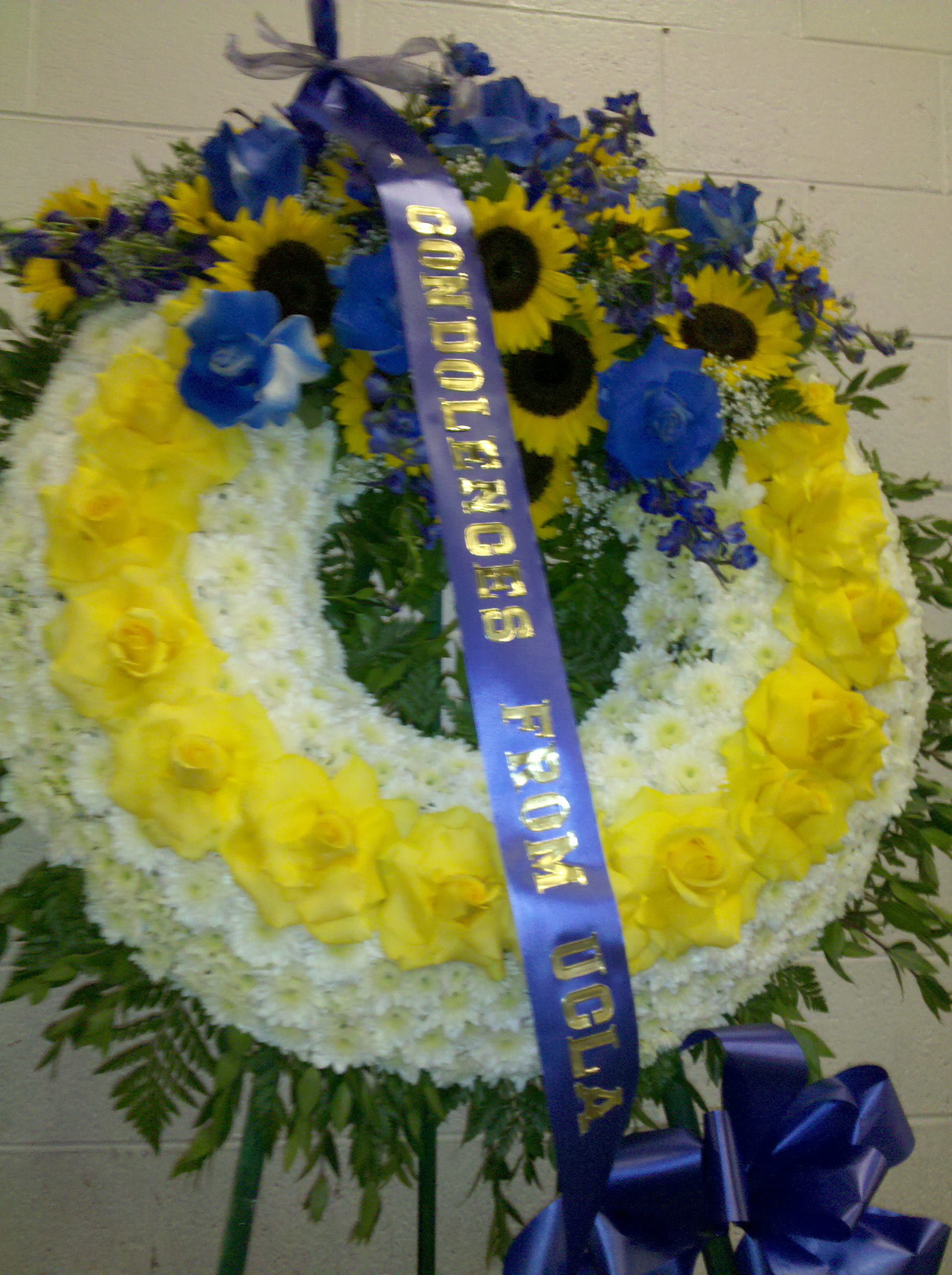 Large floral wreath with yellow roses, white flowers, and blue blooms