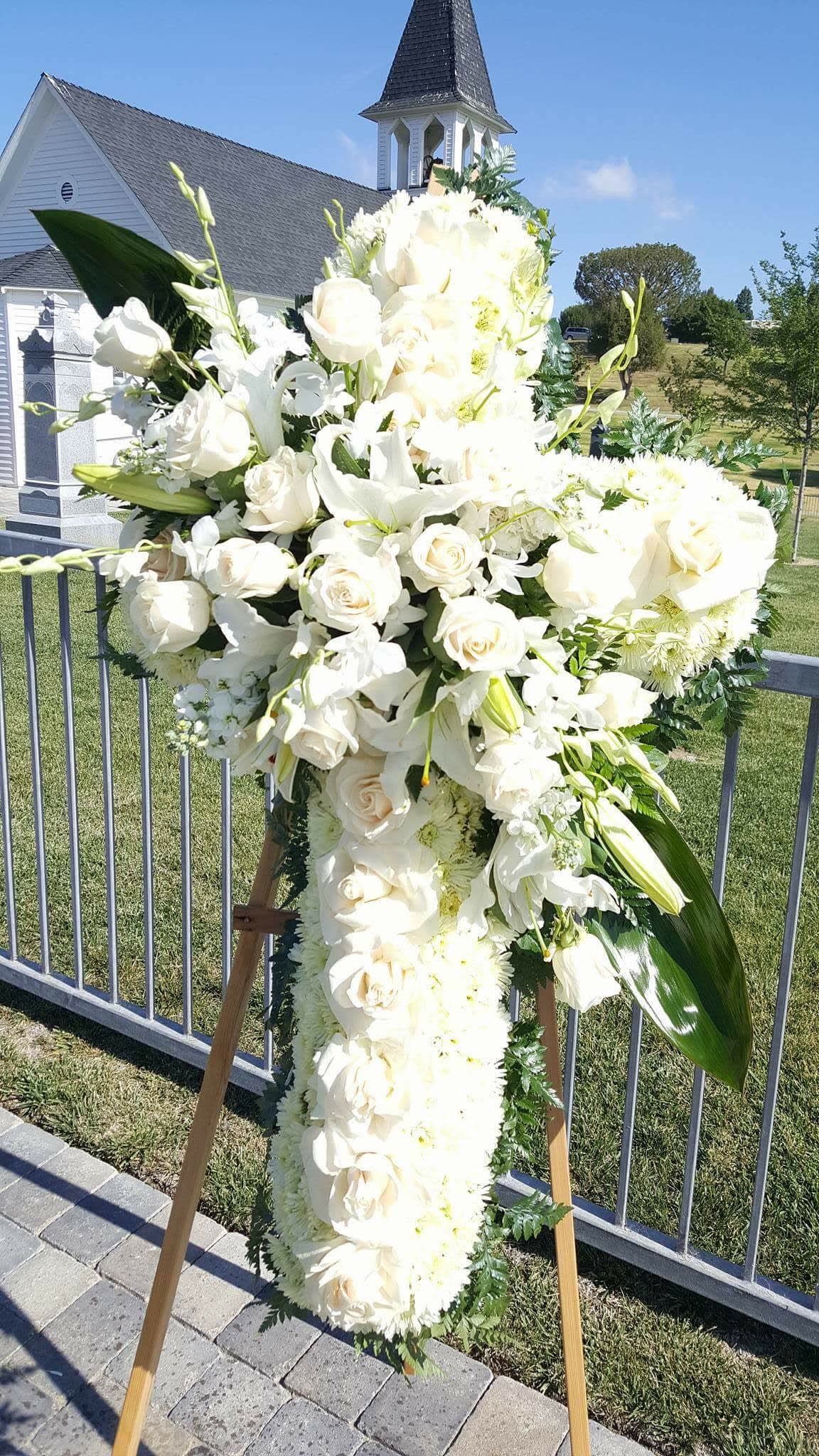 Large white funeral spray on an easel outdoors