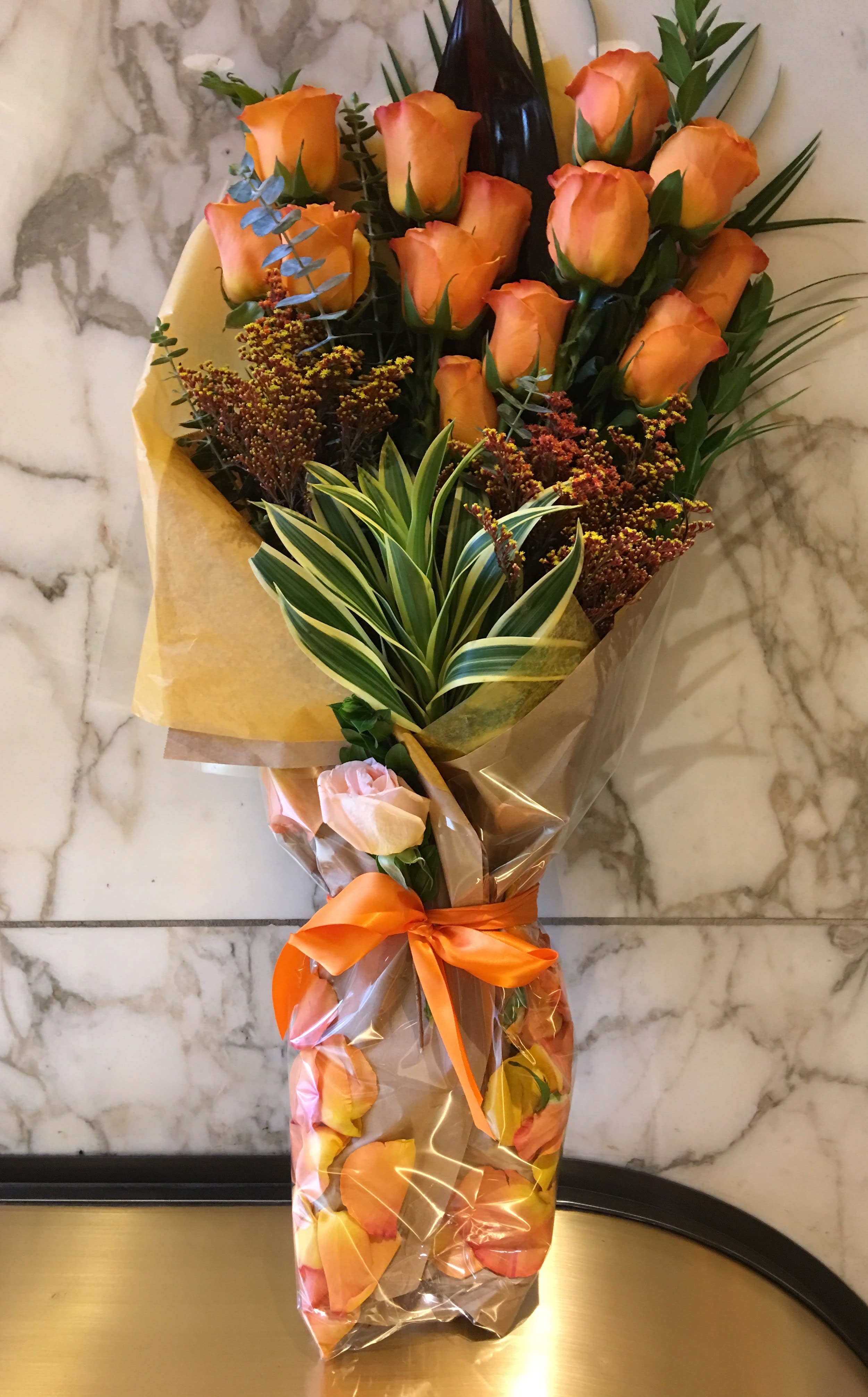 Bouquet of orange roses wrapped in clear plastic with an orange ribbon