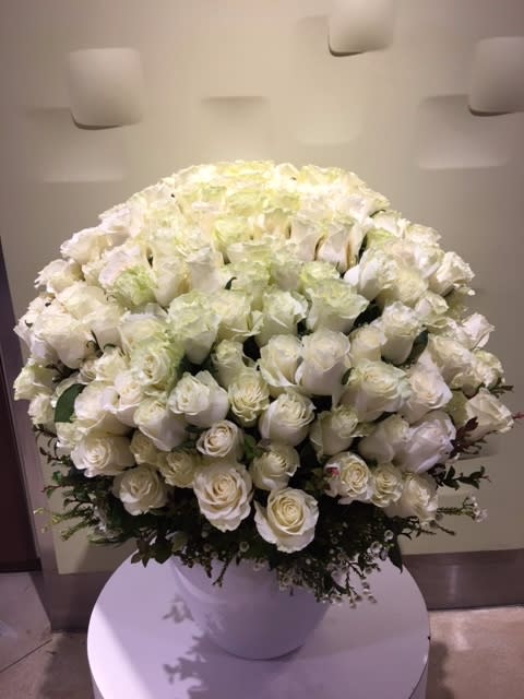 Large white rose arrangement in a white vase