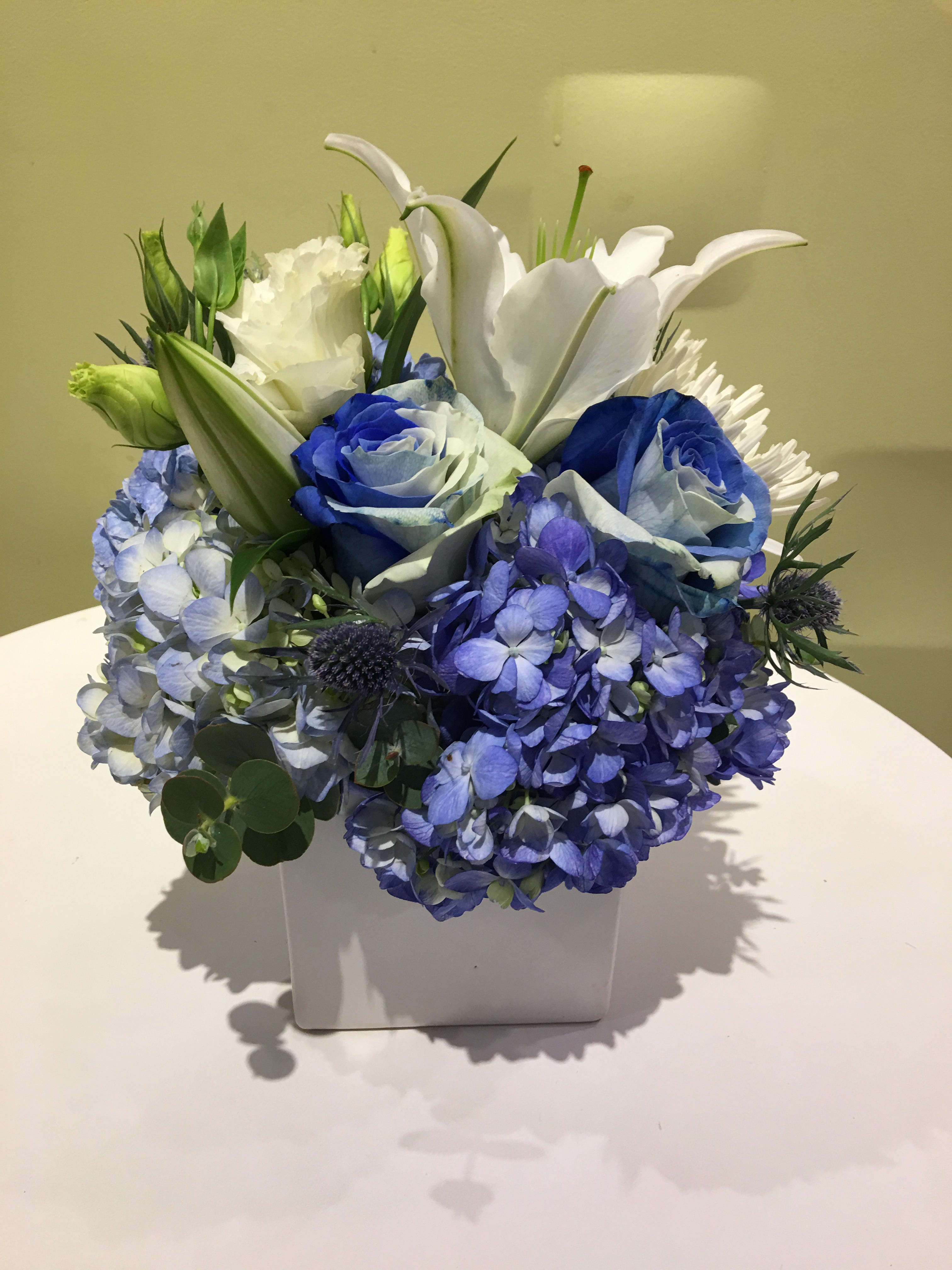 Blue and white floral arrangement in a white square vase