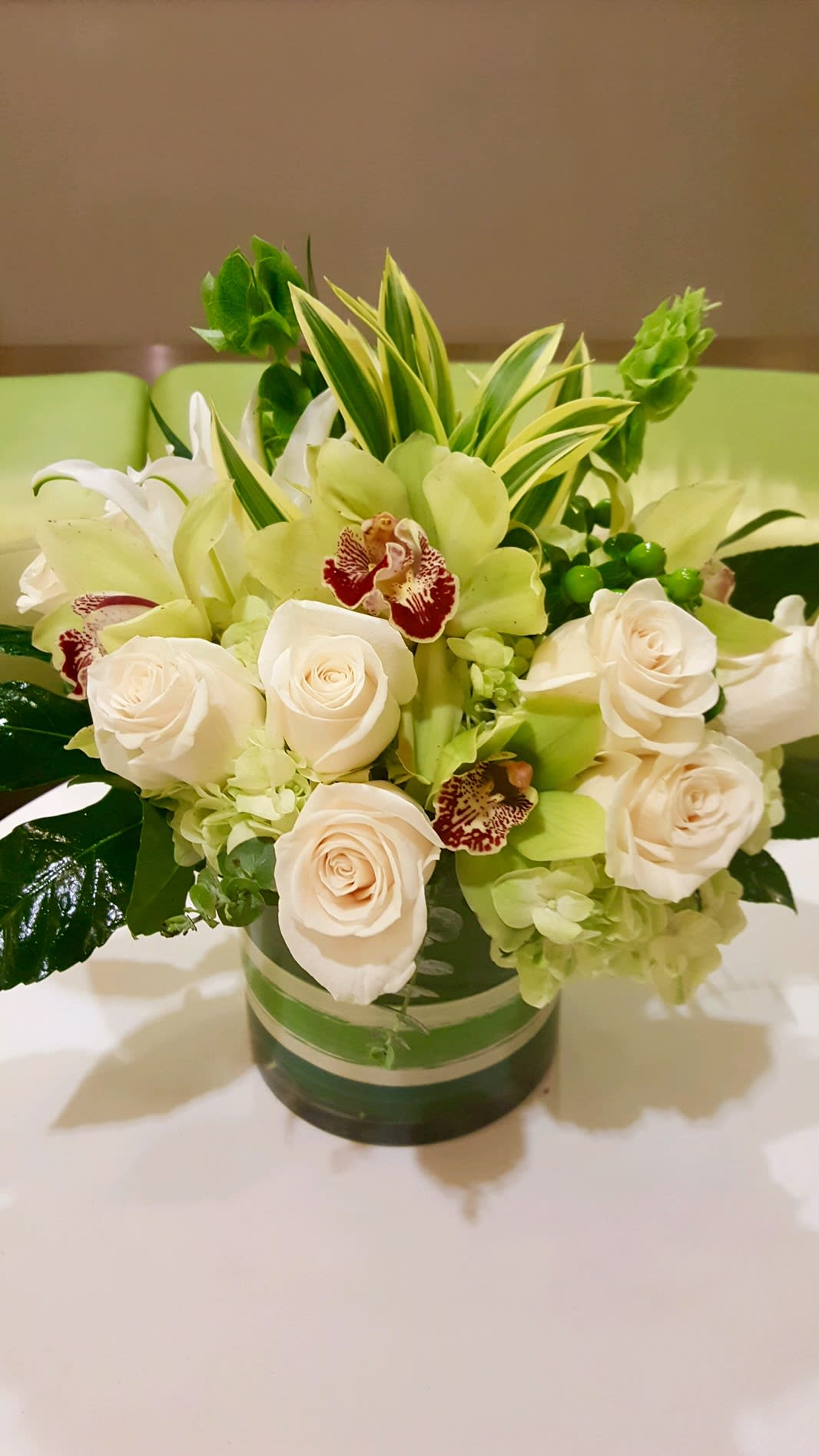 White roses and green orchids in a glass vase