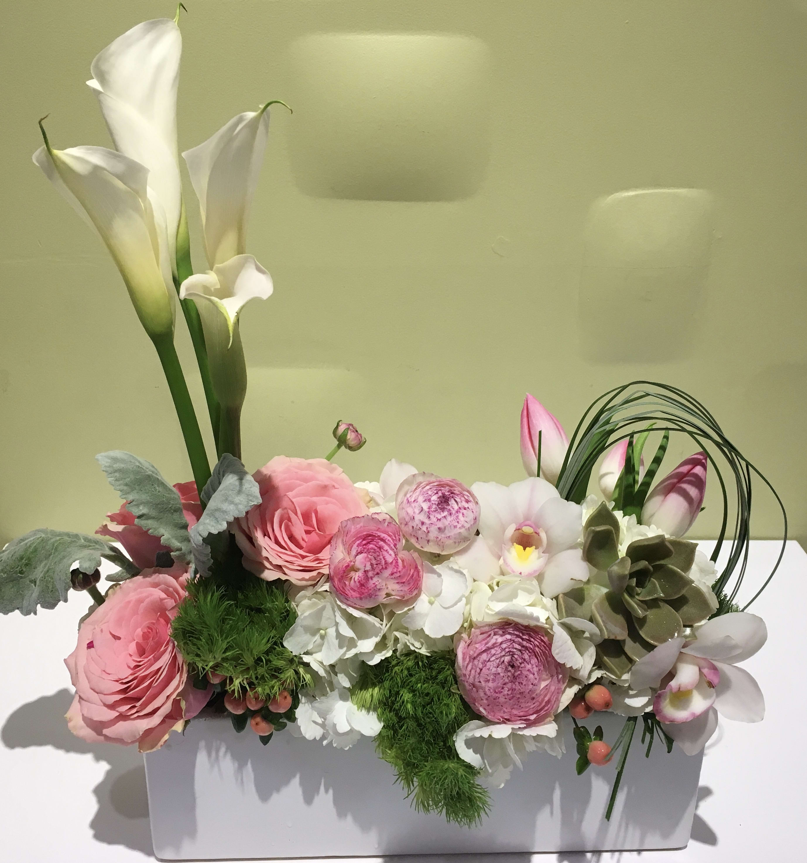 Pink and white floral arrangement in a white rectangular container