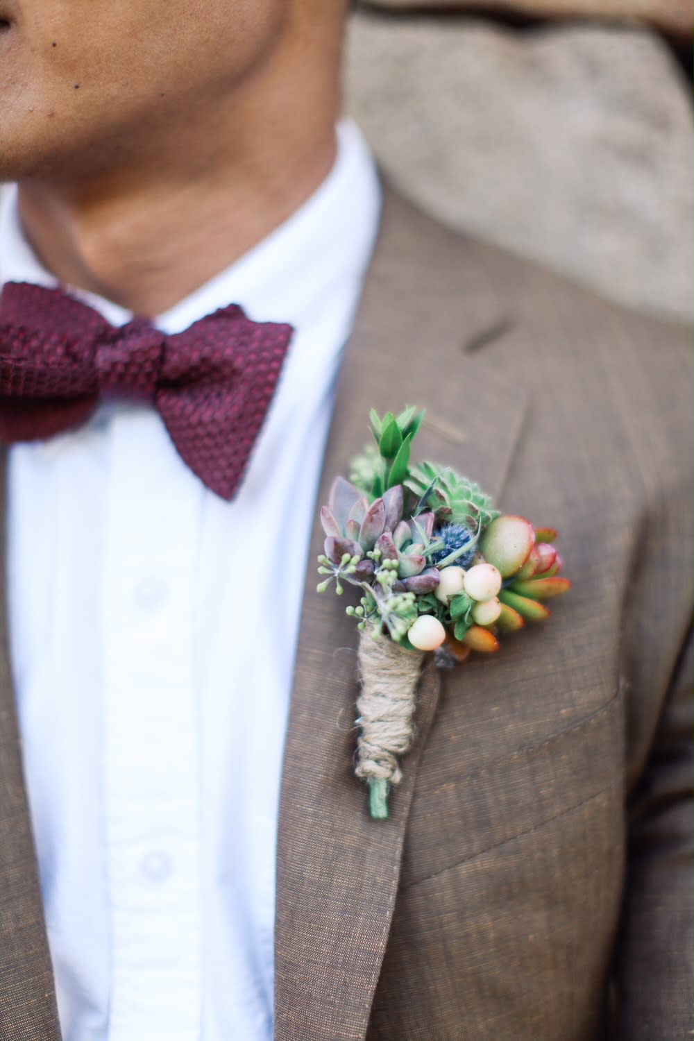 Succulent boutonniere pinned to a brown suit jacket