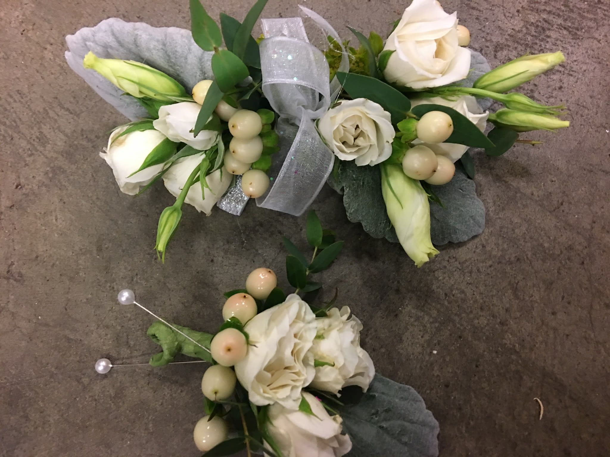 White floral corsage and boutonniere with ribbon and pearl accents