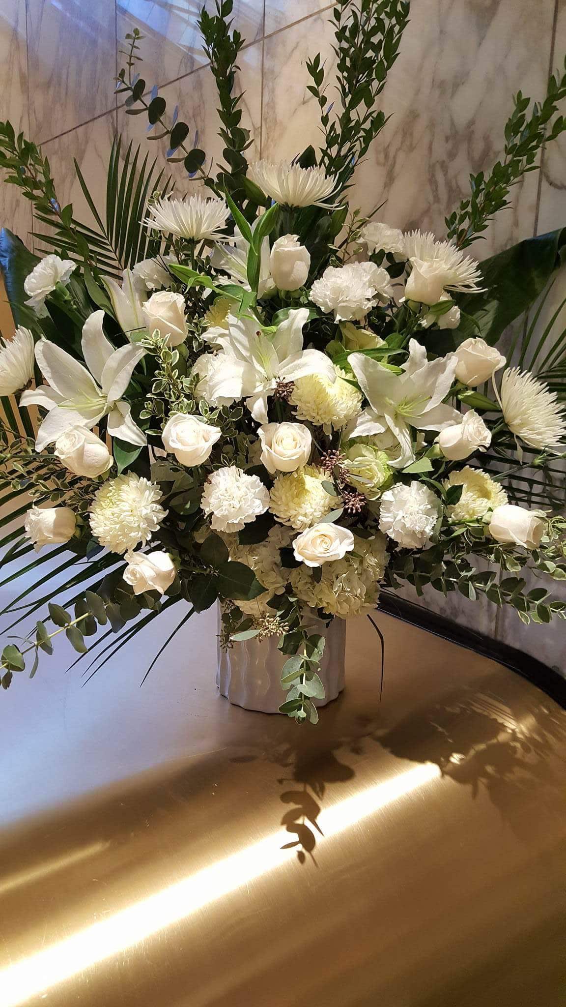 White floral arrangement with roses, lilies, and chrysanthemums in a vase