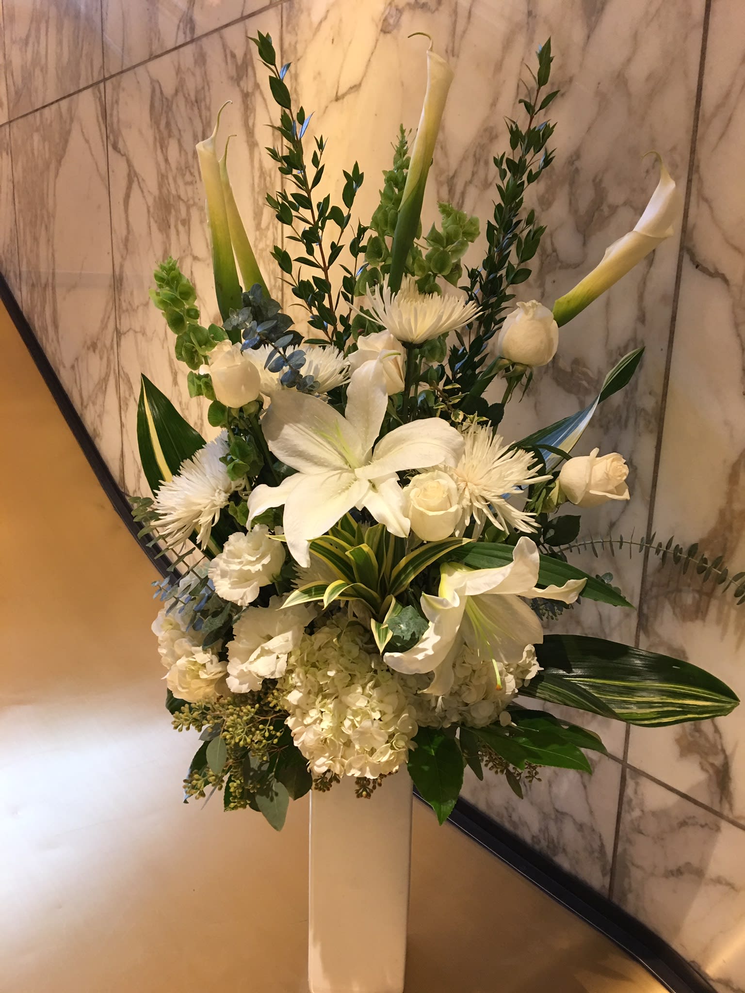 Tall white floral arrangement in a pedestal vase