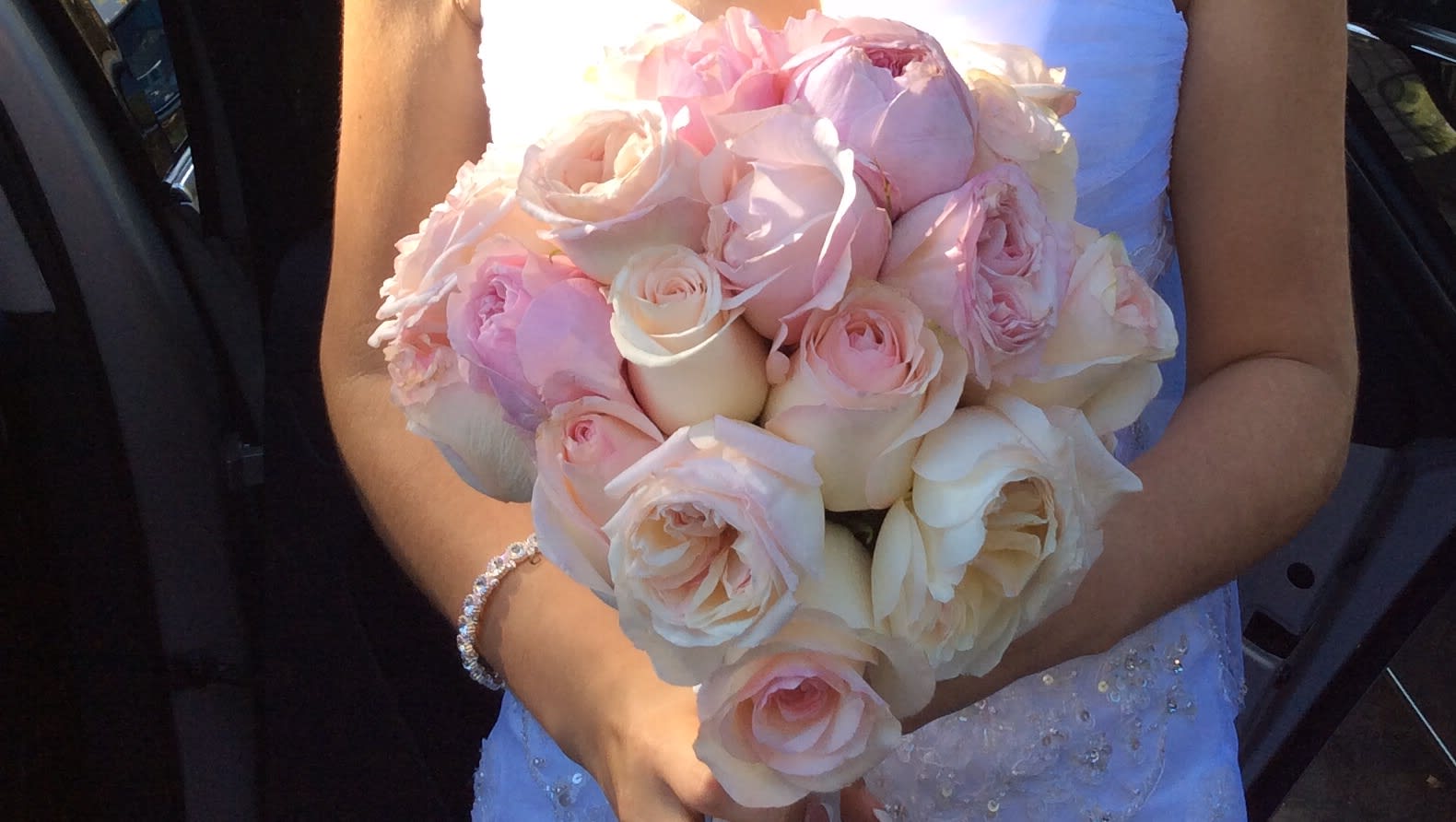Bride holding a bouquet of pale pink and ivory roses