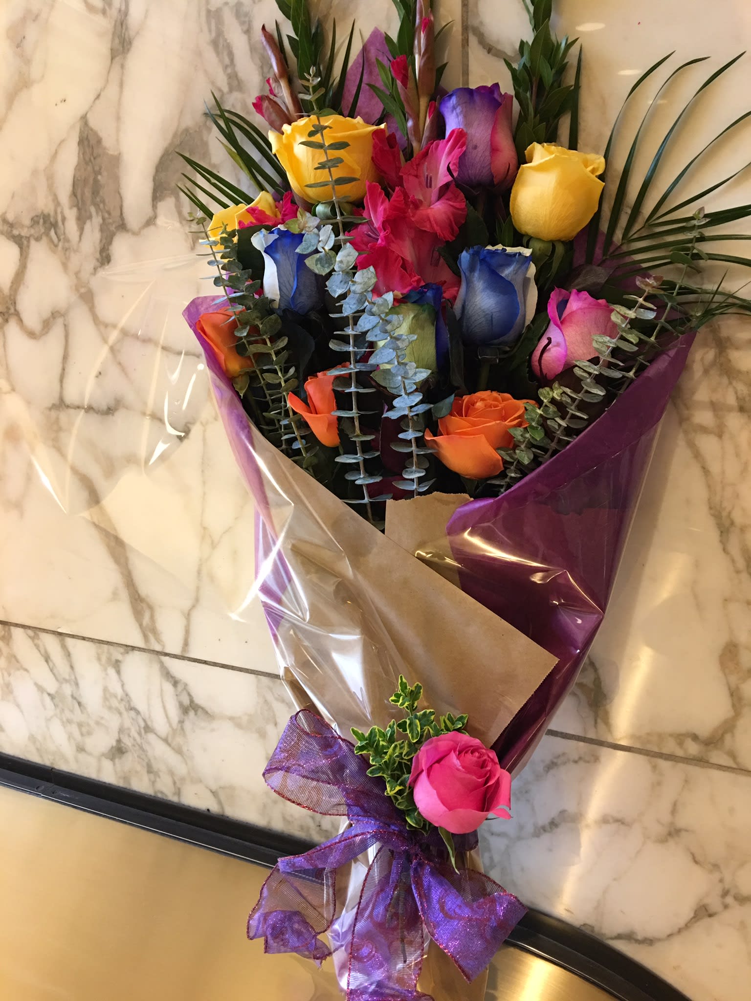 Bouquet of multicolored roses wrapped in purple and brown paper