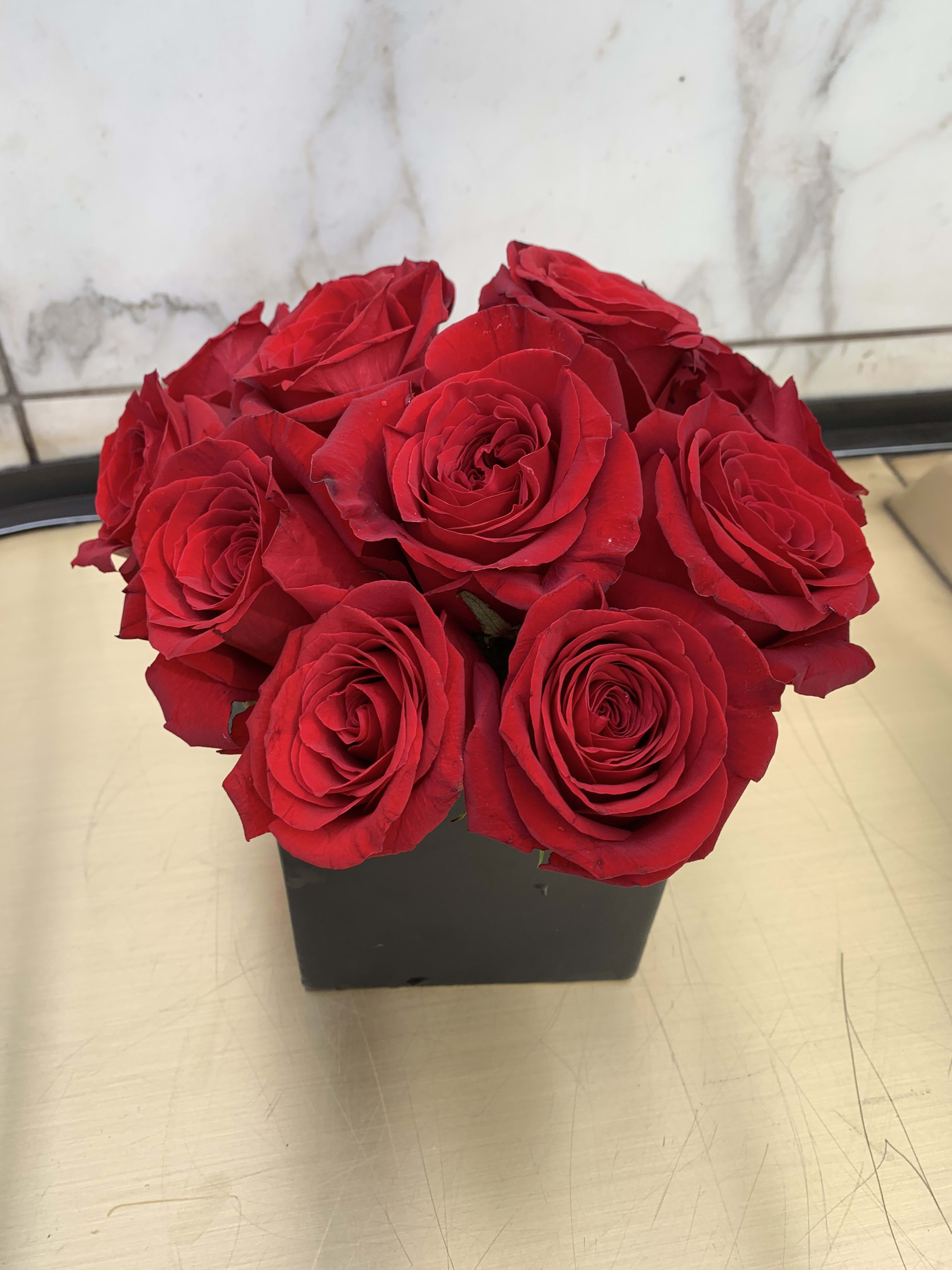 Red roses arranged in a black square vase