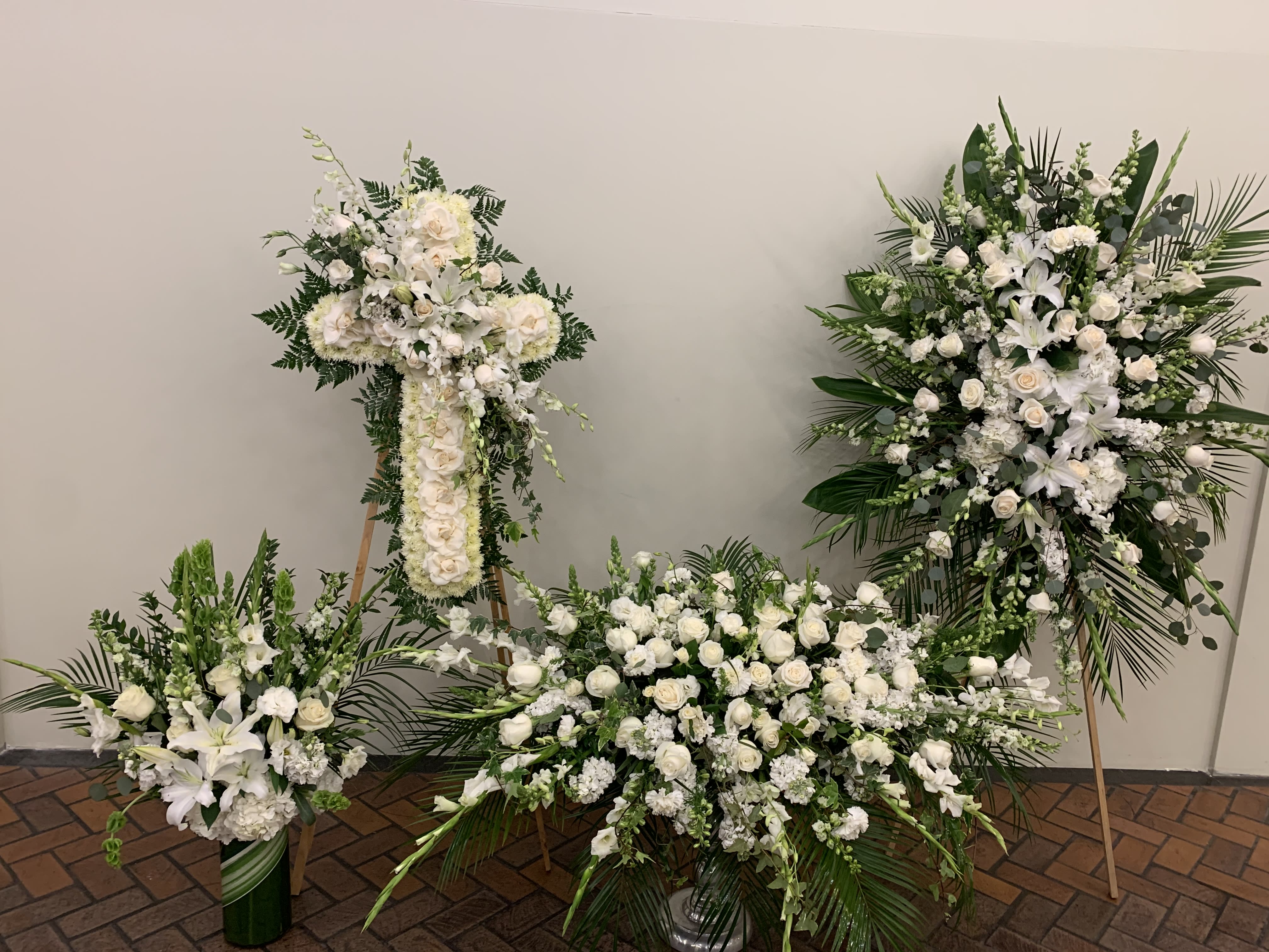 Four white floral funeral arrangements with lilies and roses