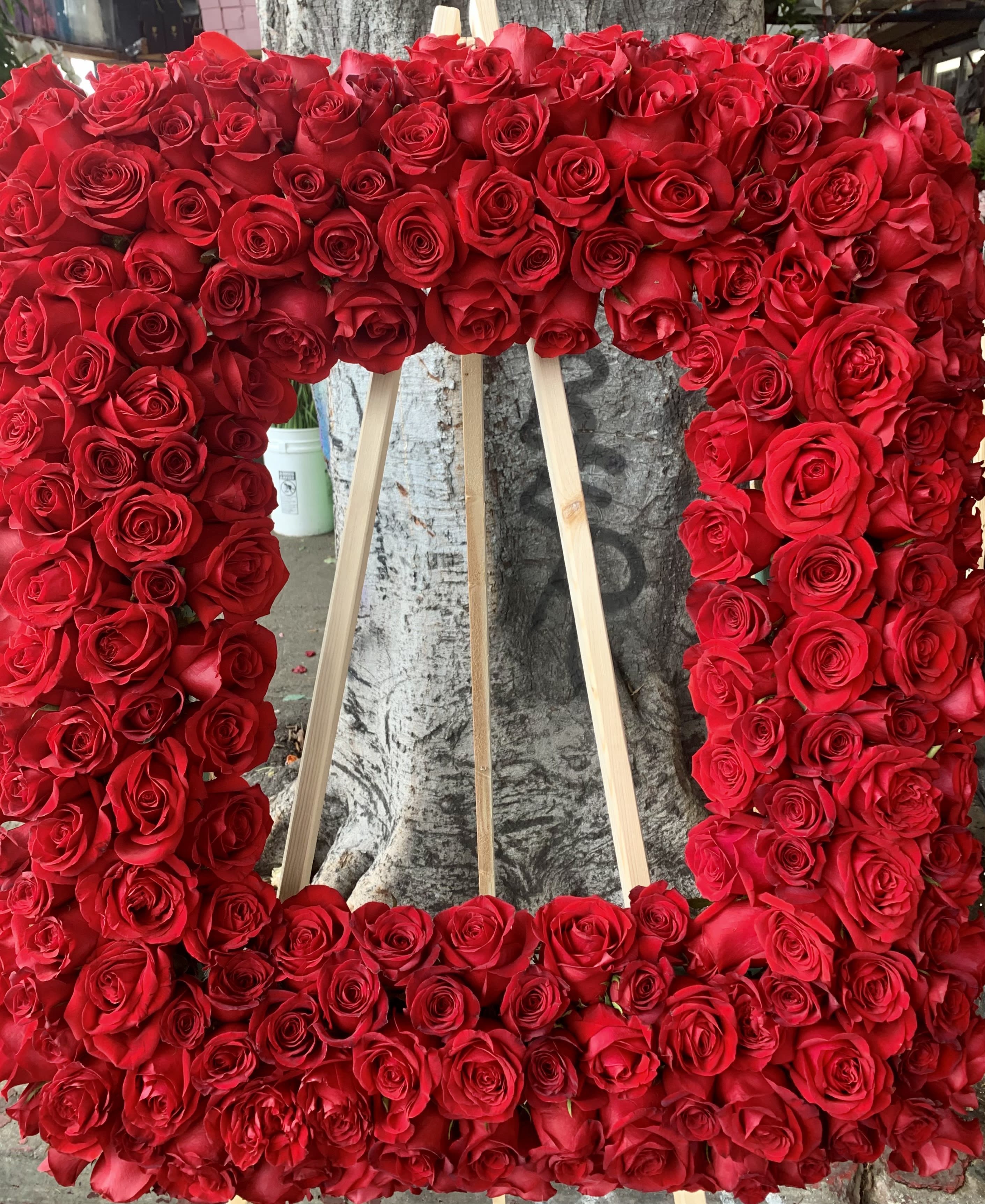 Large rectangular floral wreath of red roses on a wooden easel
