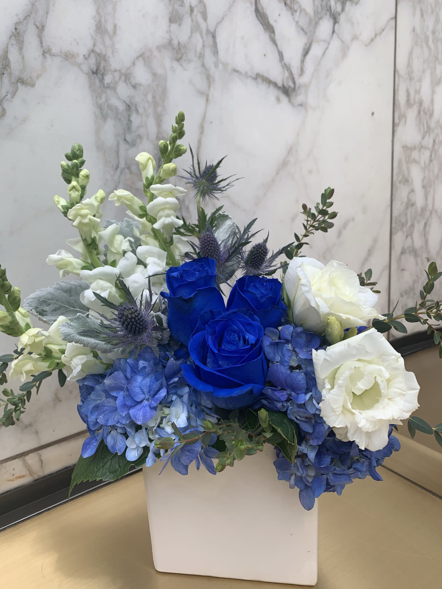 Blue and white floral arrangement in a white square vase