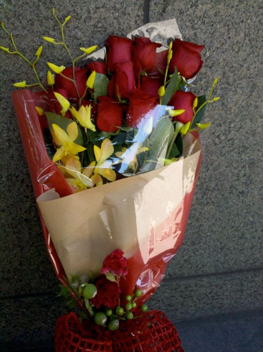 Bouquet of red roses with yellow orchids wrapped in paper