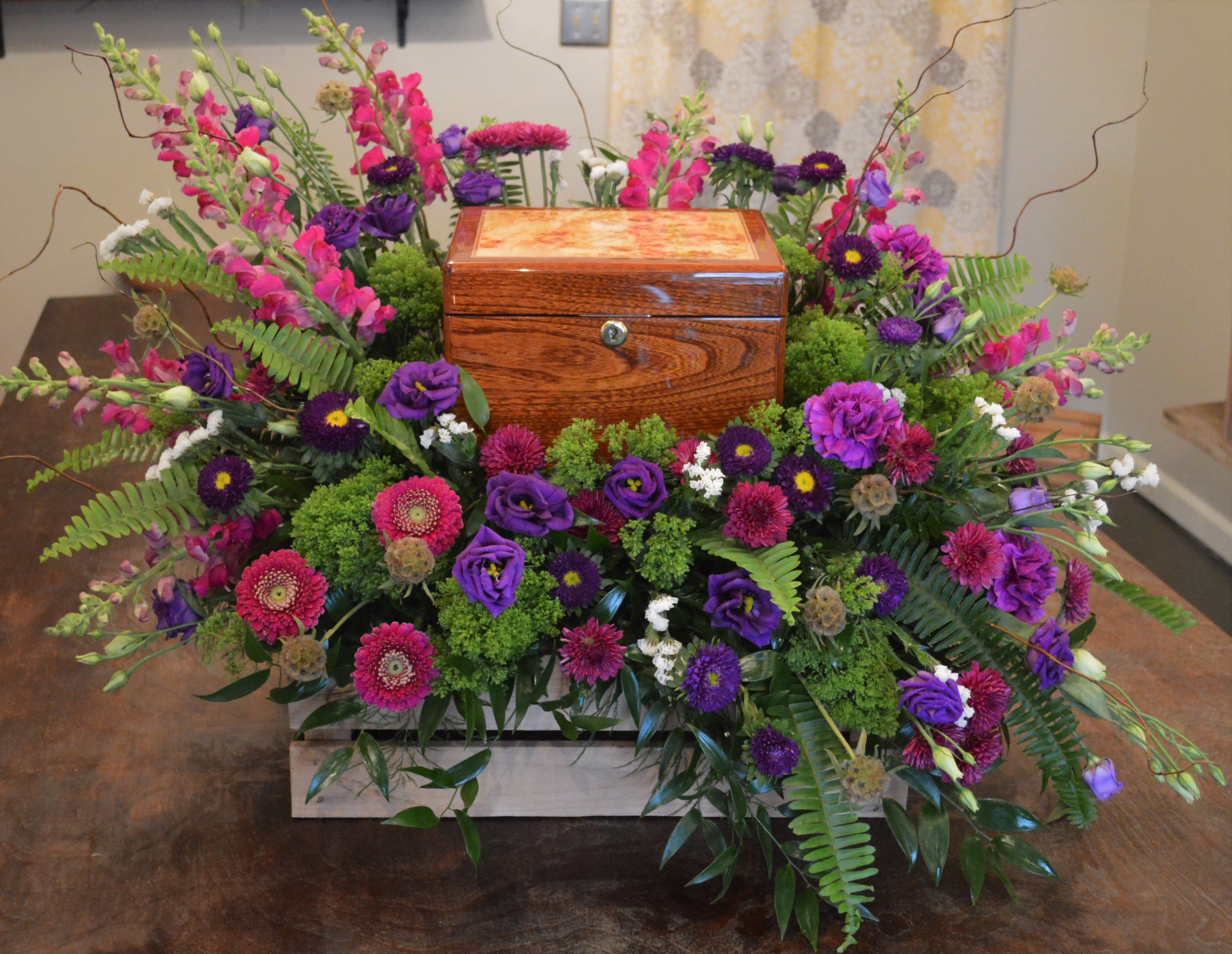 Colorful floral arrangement surrounding a wooden urn box