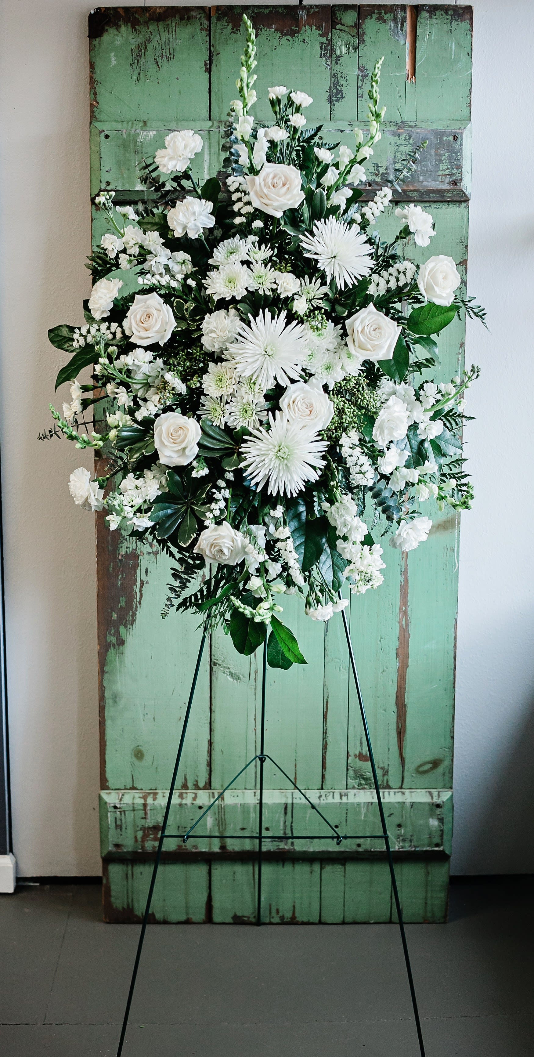 White floral standing spray on a black easel