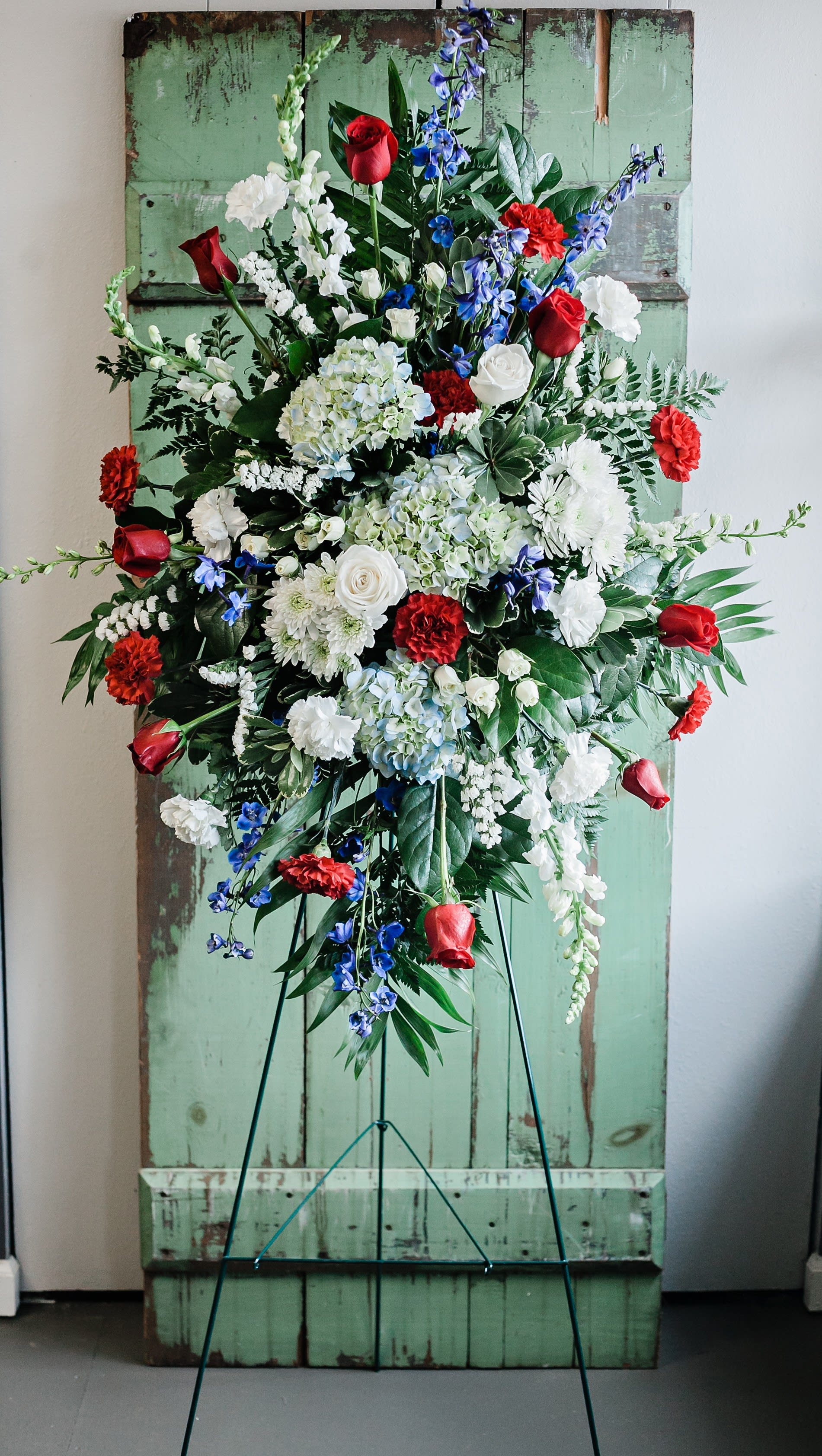 Large standing floral spray with red, white, and blue flowers on an easel.