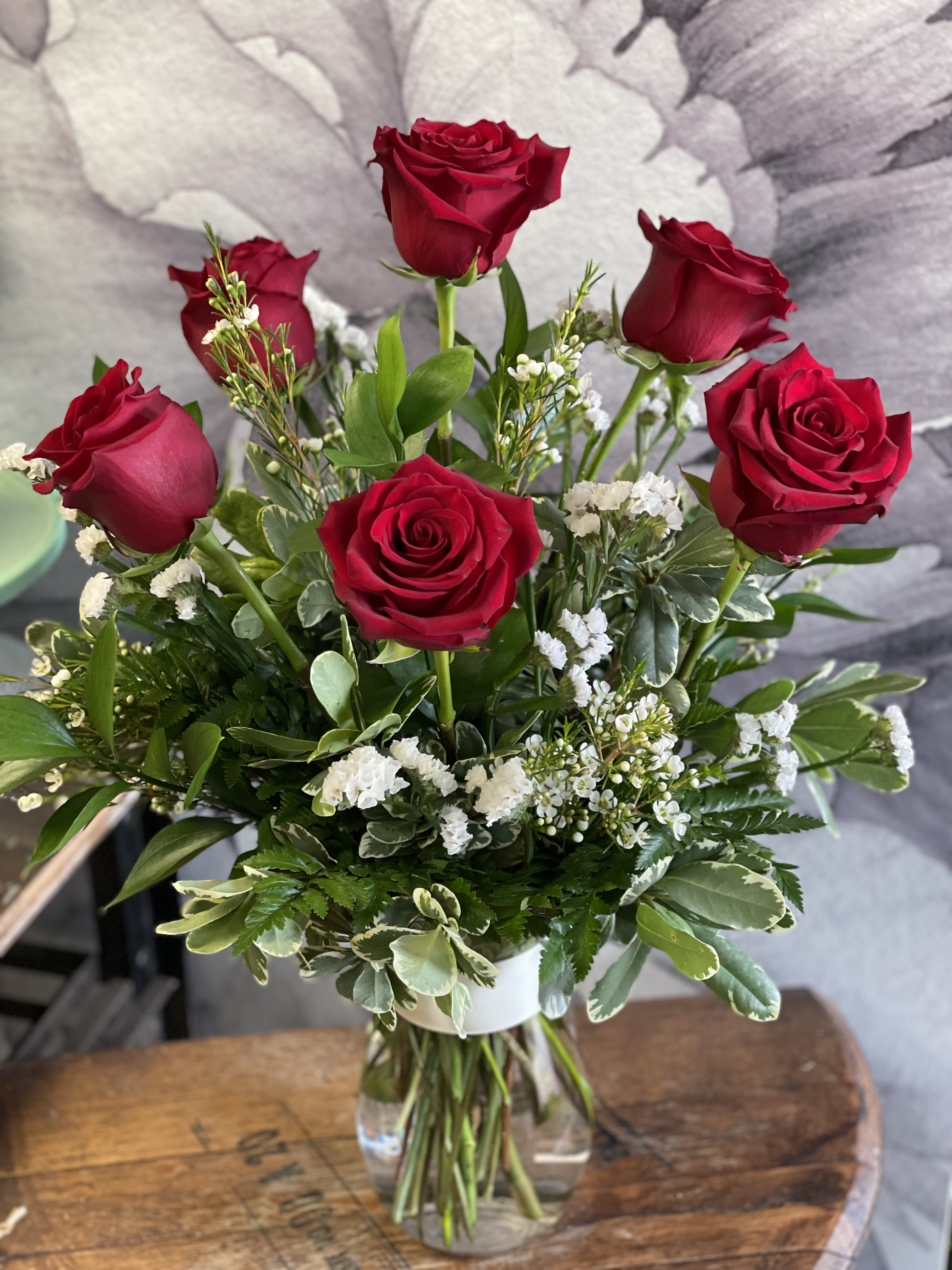 Red roses arranged in a clear glass vase with white filler flowers