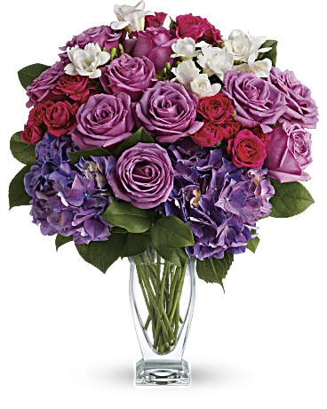 Bouquet of pink and purple roses with white flowers in a clear glass vase