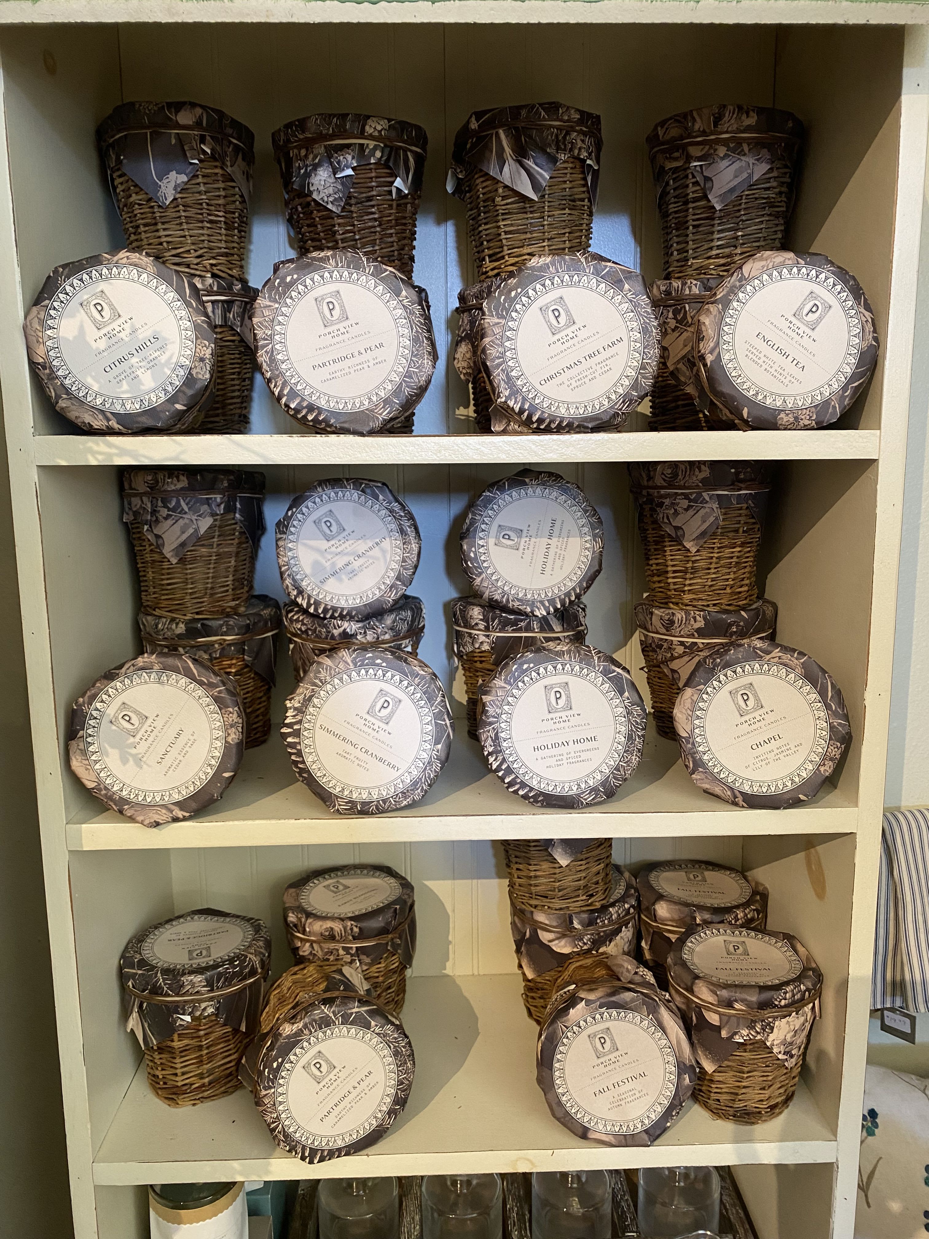 Shelves of wicker-wrapped candles with round labeled lids
