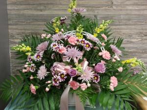 Pink and lavender funeral spray with mixed flowers and greenery