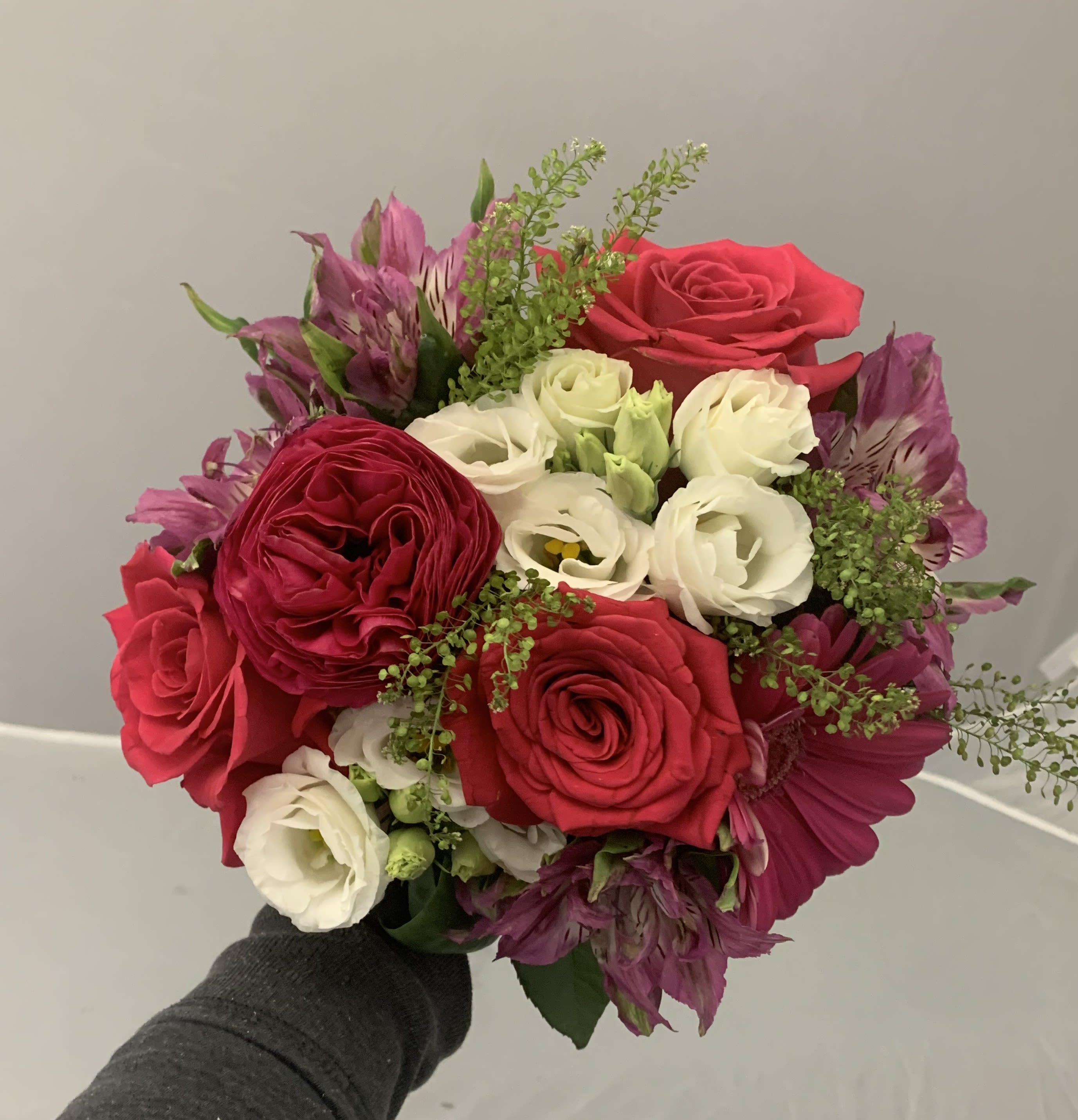Handheld bouquet of red and white roses with purple flowers