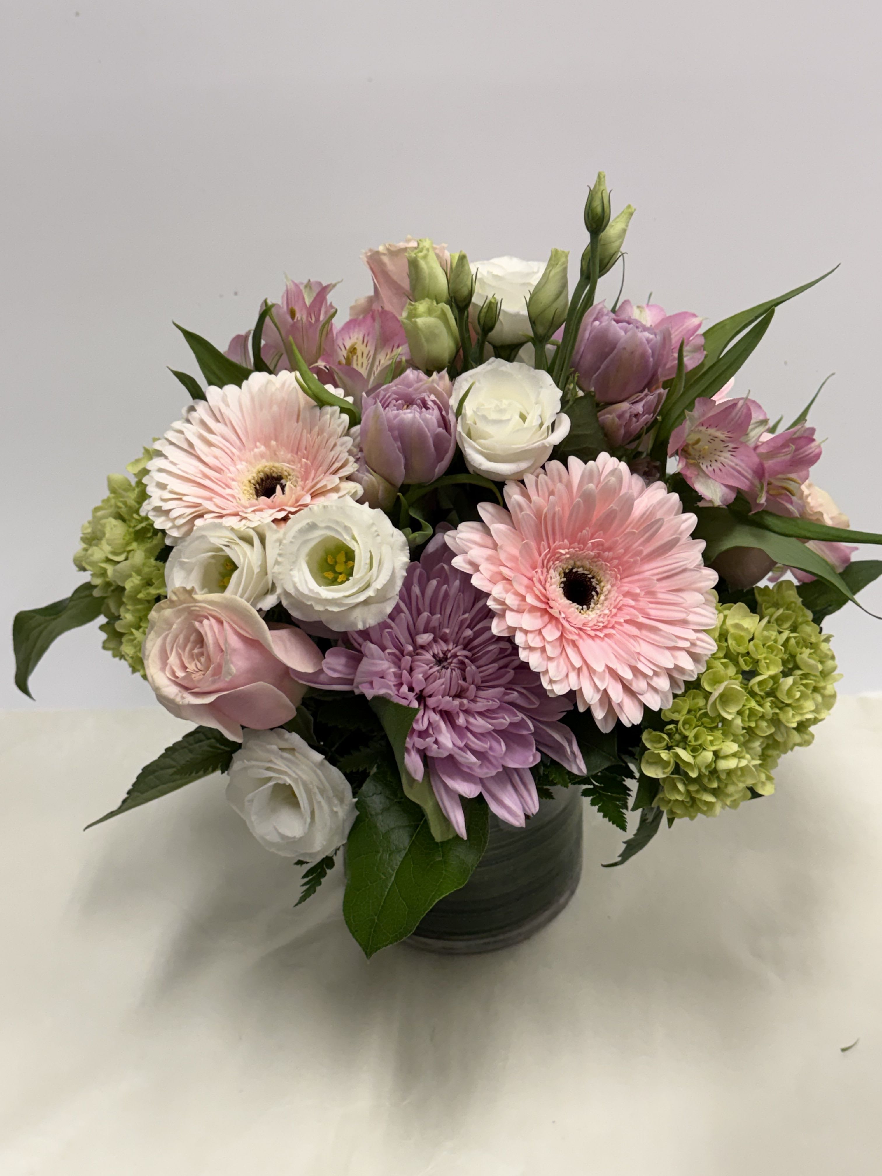 PFM Pastel  - A lovely combination of pastels arranged in a compact pink gerberas, roses, hydrangeas, double tulips, lisianthus, cremons, alstroemeria, and other seasonal flowers.  Standard is in a 5x5 leaf-lined cylinder/cube.  Deluxe is in a 5x5 leaf-lined cylinder/cube.  Premium is in a 6x6 leaf-lined cylinder/cube. 