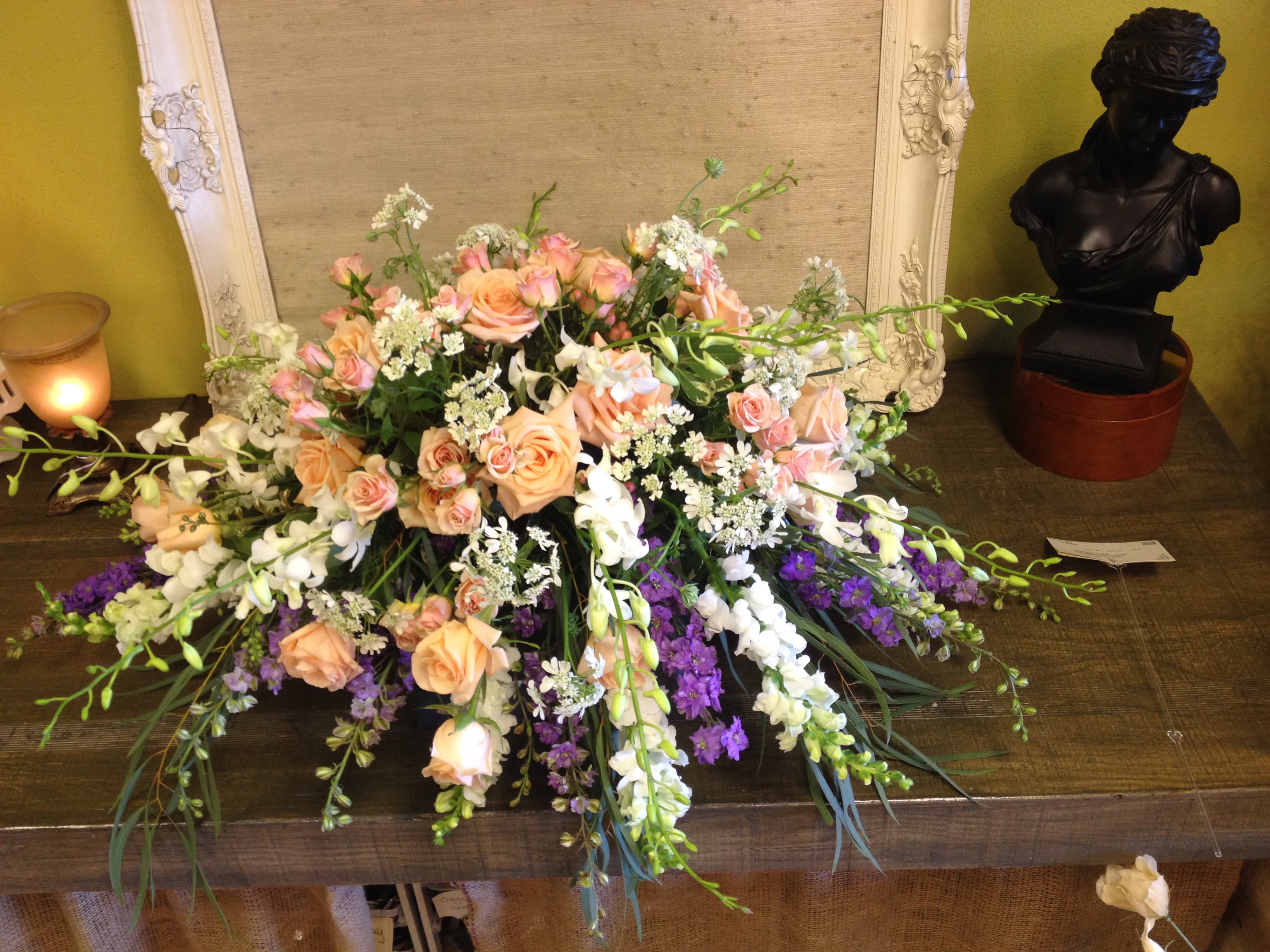Low floral arrangement with peach roses, white blooms, and purple flowers