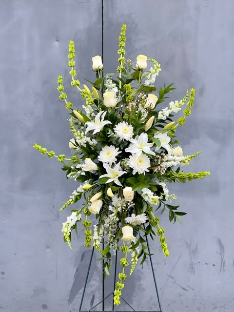 Tall white floral spray on a stand with green accents